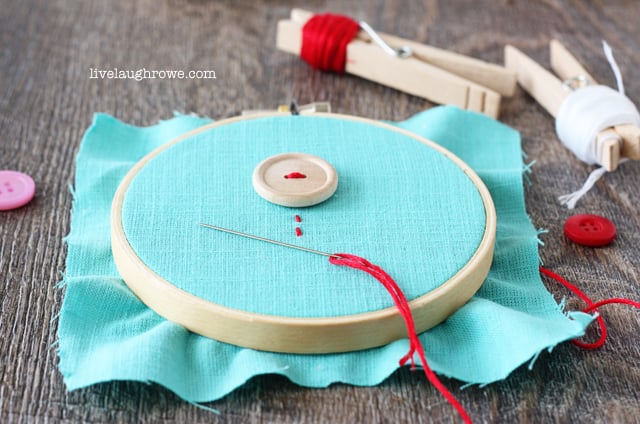 Sewing on buttons as flowers to fabric for Valentine's Day Embroidery Hoop Art