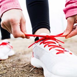 Person tying running shoes outdoors, symbolizing walking 10,000 steps a day as part of a healthy routine.