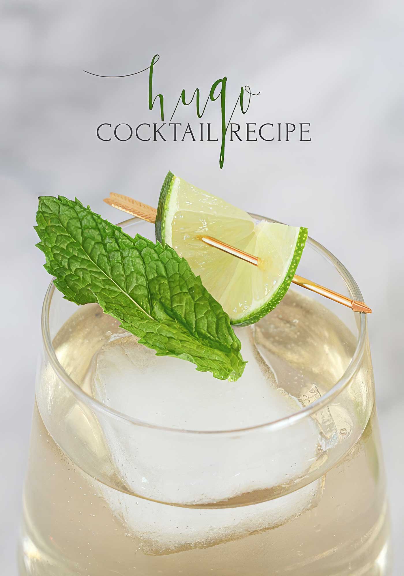 Hugo Spritz cocktail garnished with fresh mint and lime with Hugo cocktail recipe text above.