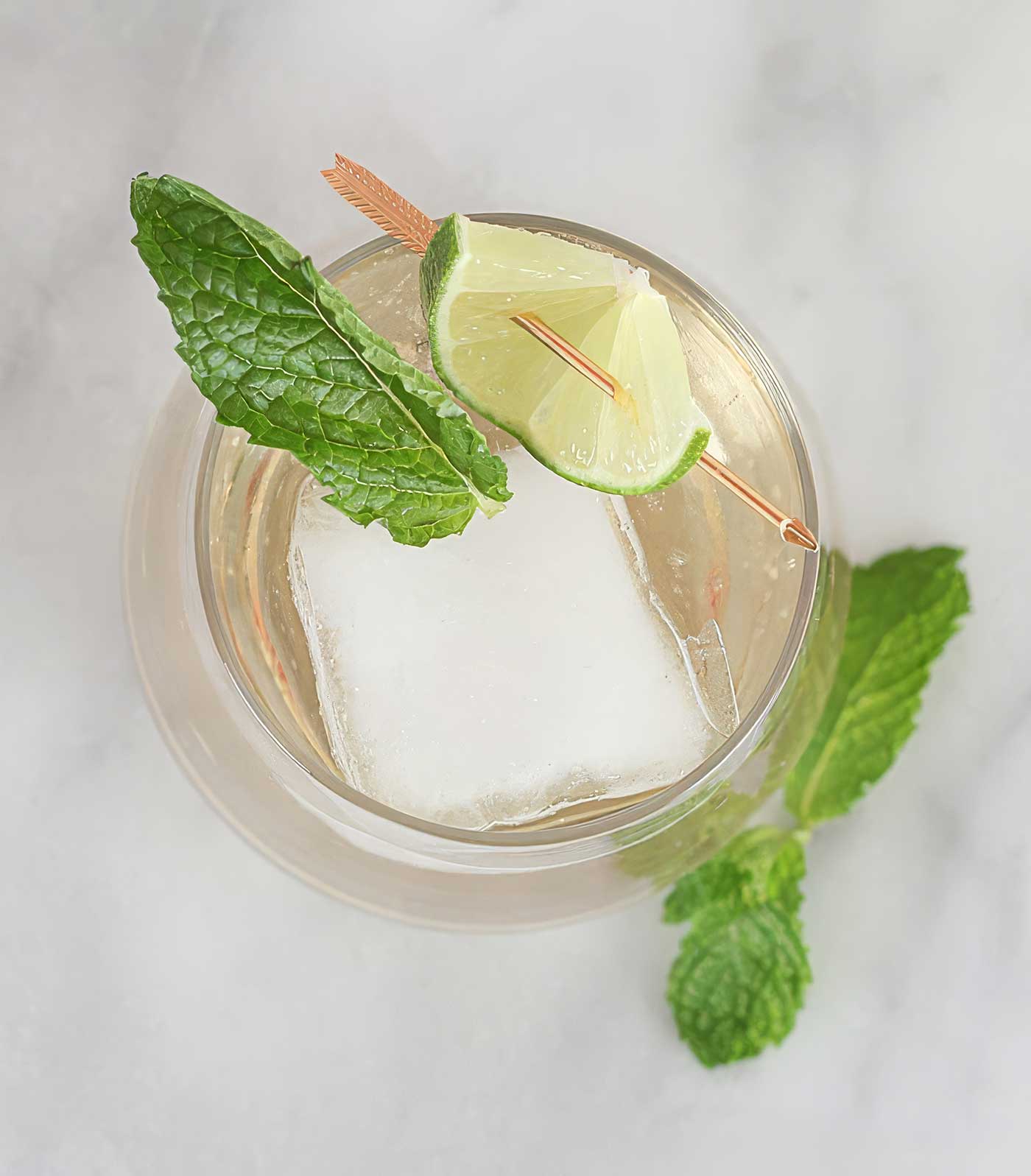 Overhead view of a Hugo Spritz with ice, fresh mint, and lime garnish.