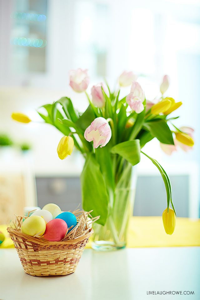 Image of colored Easter eggs in basket and bunch of tulips near from GraphicStock.com