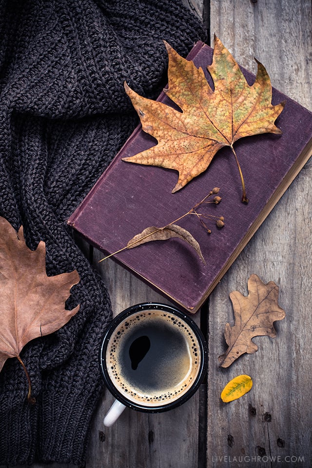 Old book, knitted sweater with autumn leaves and coffee mug