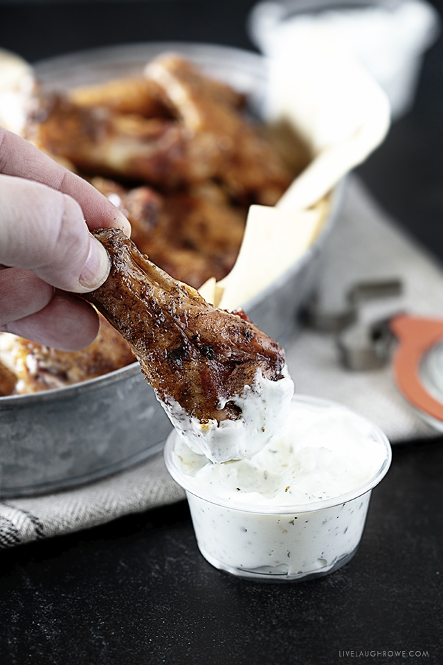 Smoked Chicken Wing being dipped into sauce.