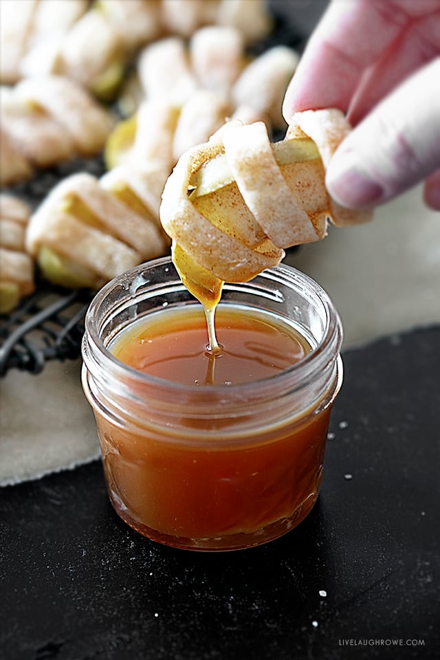 Dipping a mini apple pie into caramel sauce