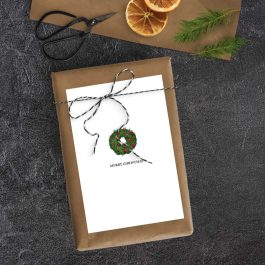 Brown-paper wrapped Christmas gift topped with black-and-white twine and a minimalist printable wreath card