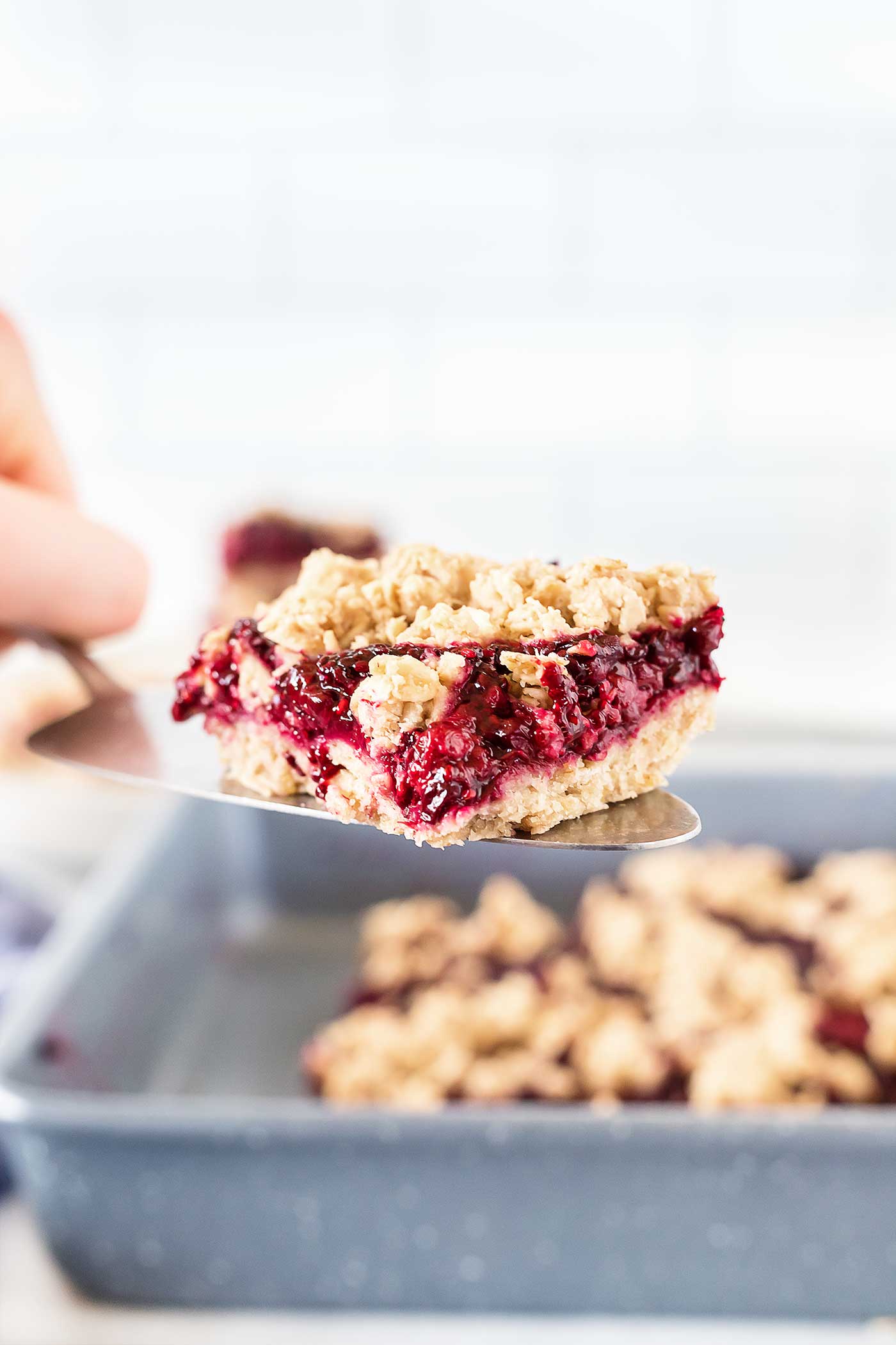 Hand serving a piece of Homemade Oatmeal Bars with Blackberries