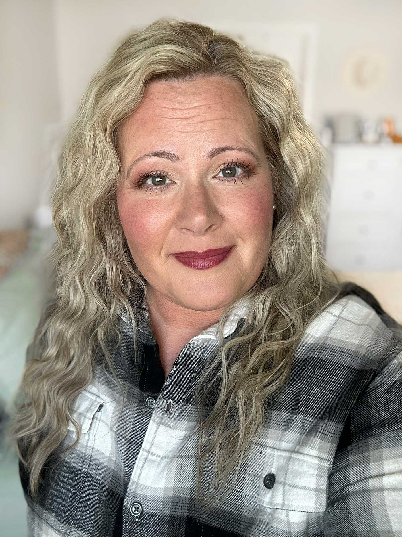 woman's headshot with wavy blonde hair and a dark lipstick