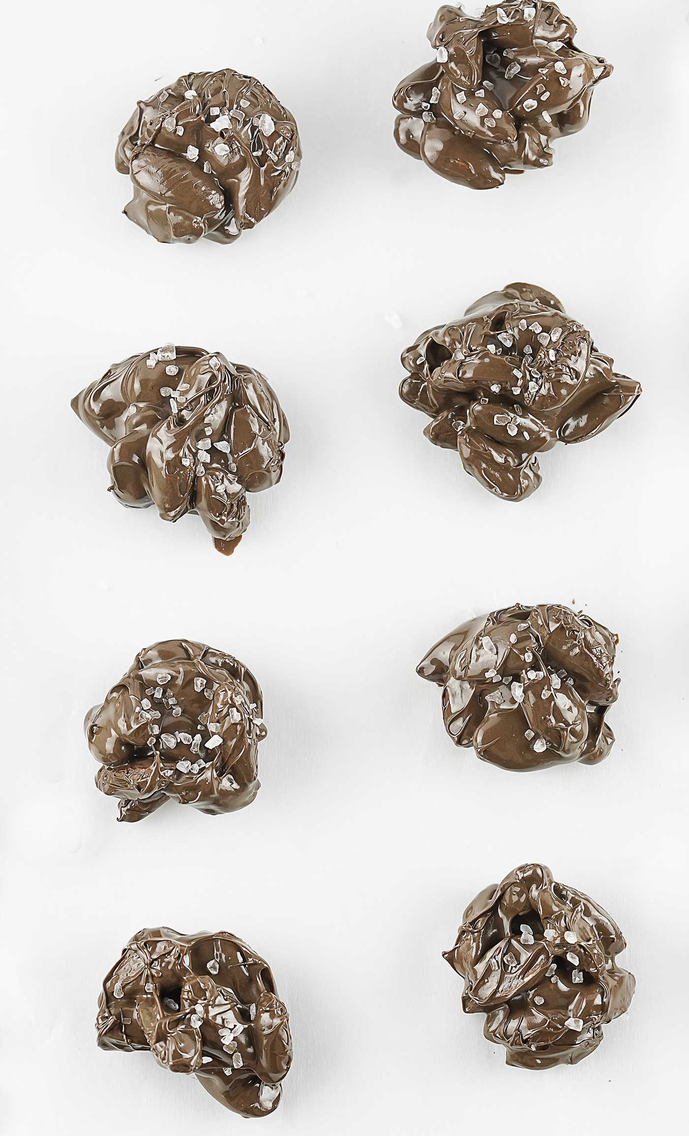 Placing scoops of almond clusters on parchment paper.