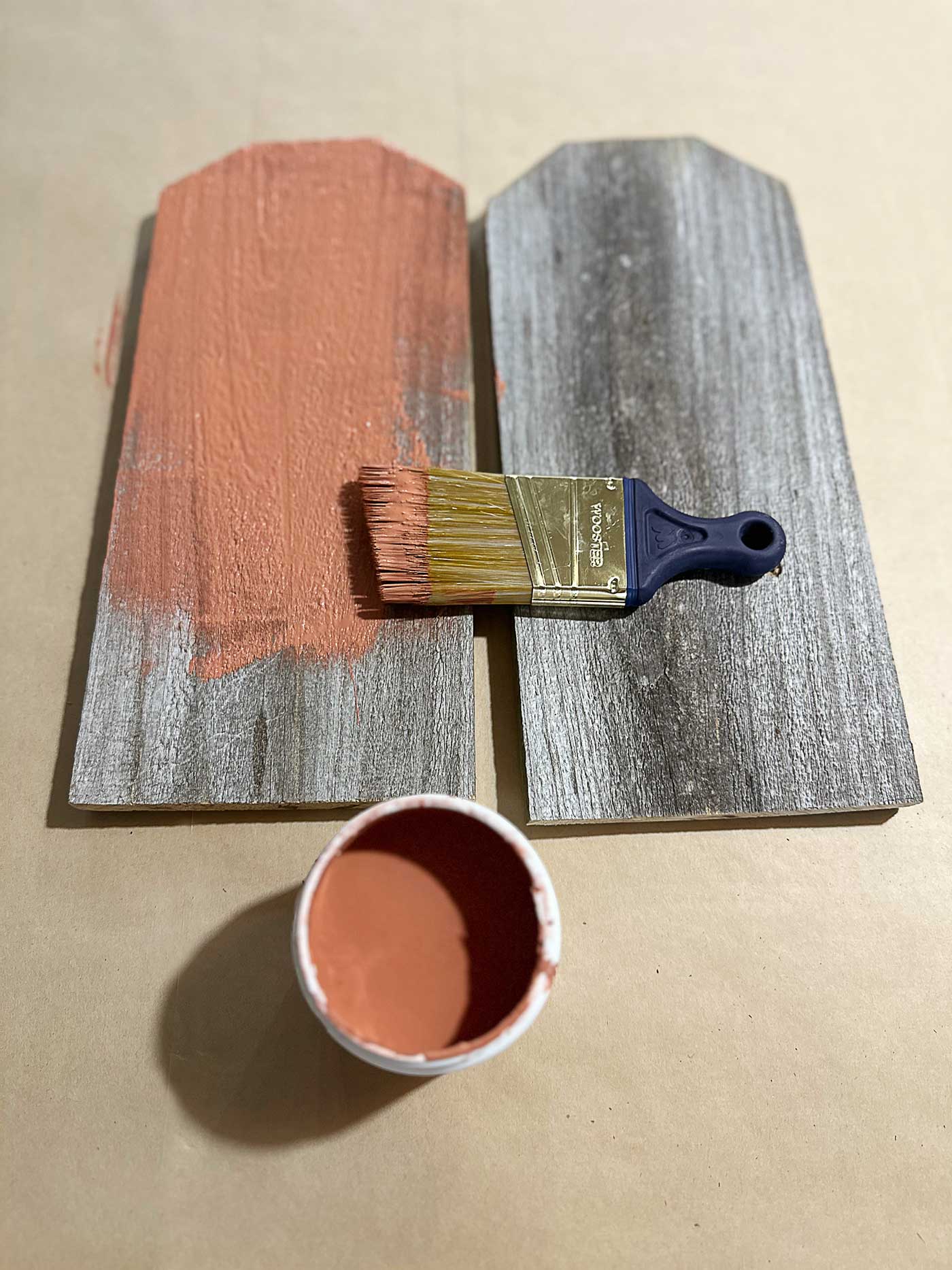 terracotta color paint going on weathered fence picket