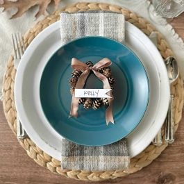 fall place setting with a foraged place card holder on a blue plate with a fall napkin and white dinner plate