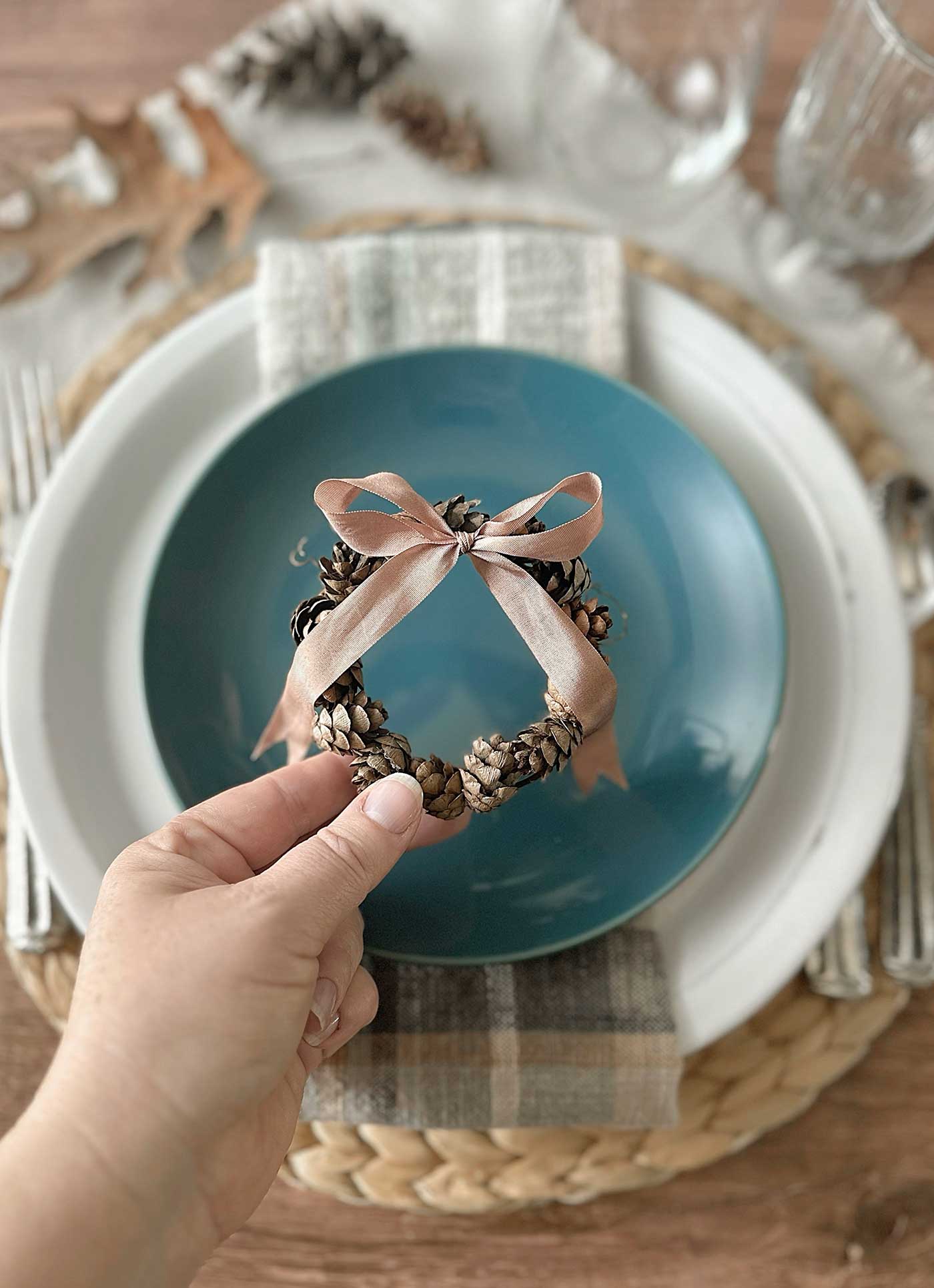 placing a pinecone wreath onto a plate