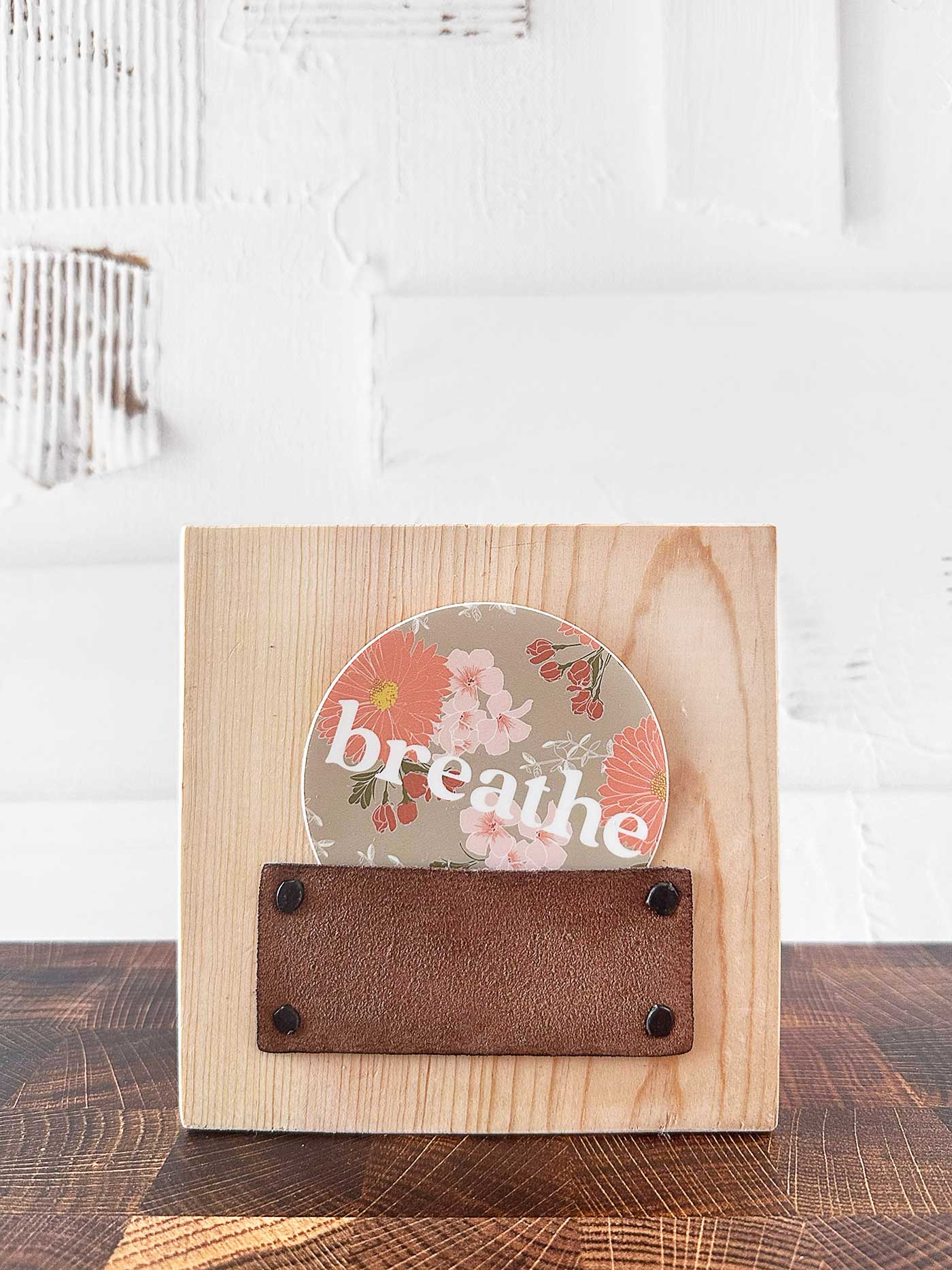 using the air plant holder as a small desk wood plaque holding a sticker that says breath