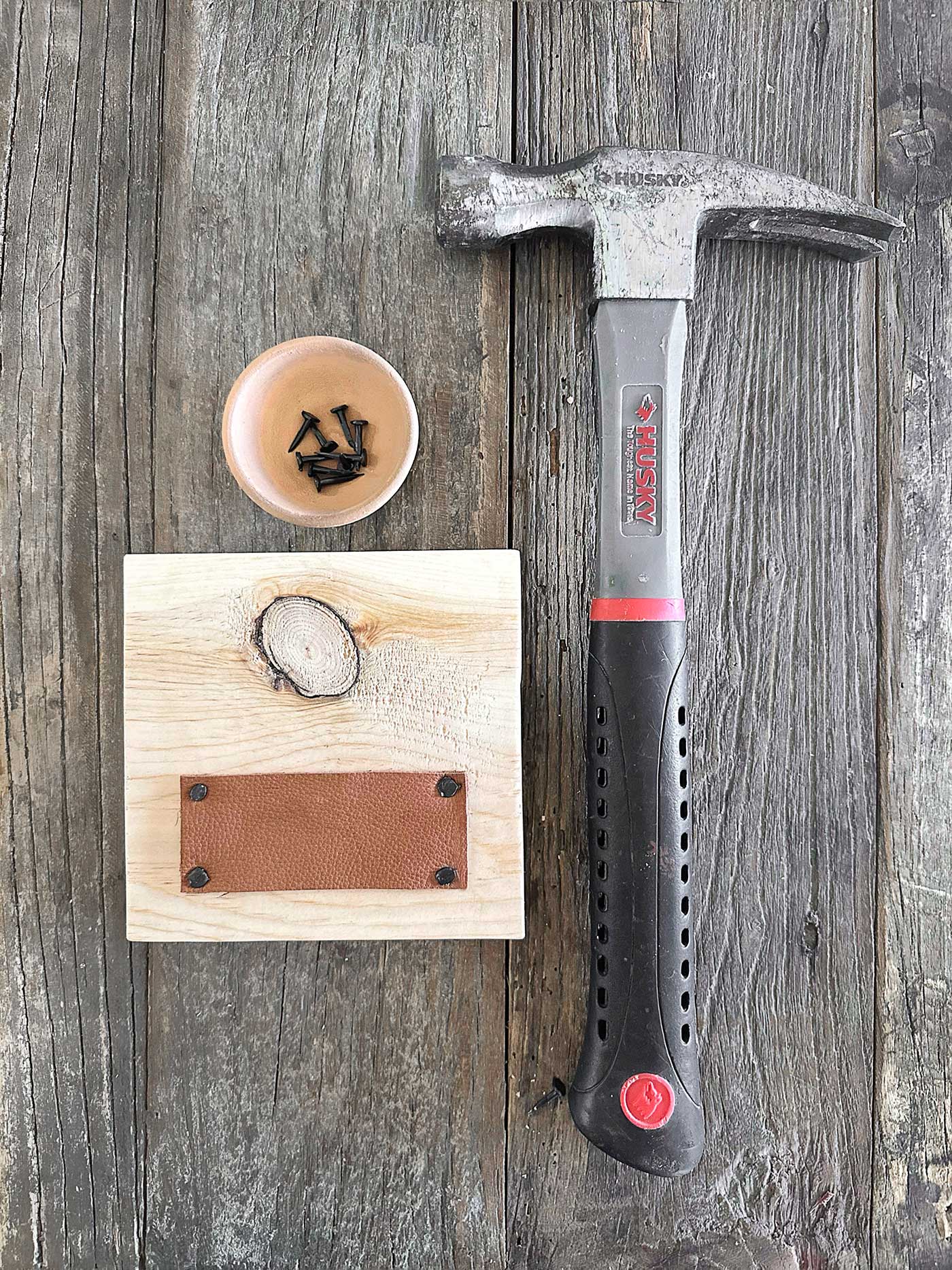 carpet tack nails and a strip of leather that will be attached to the wood plaque pictured using the hammer