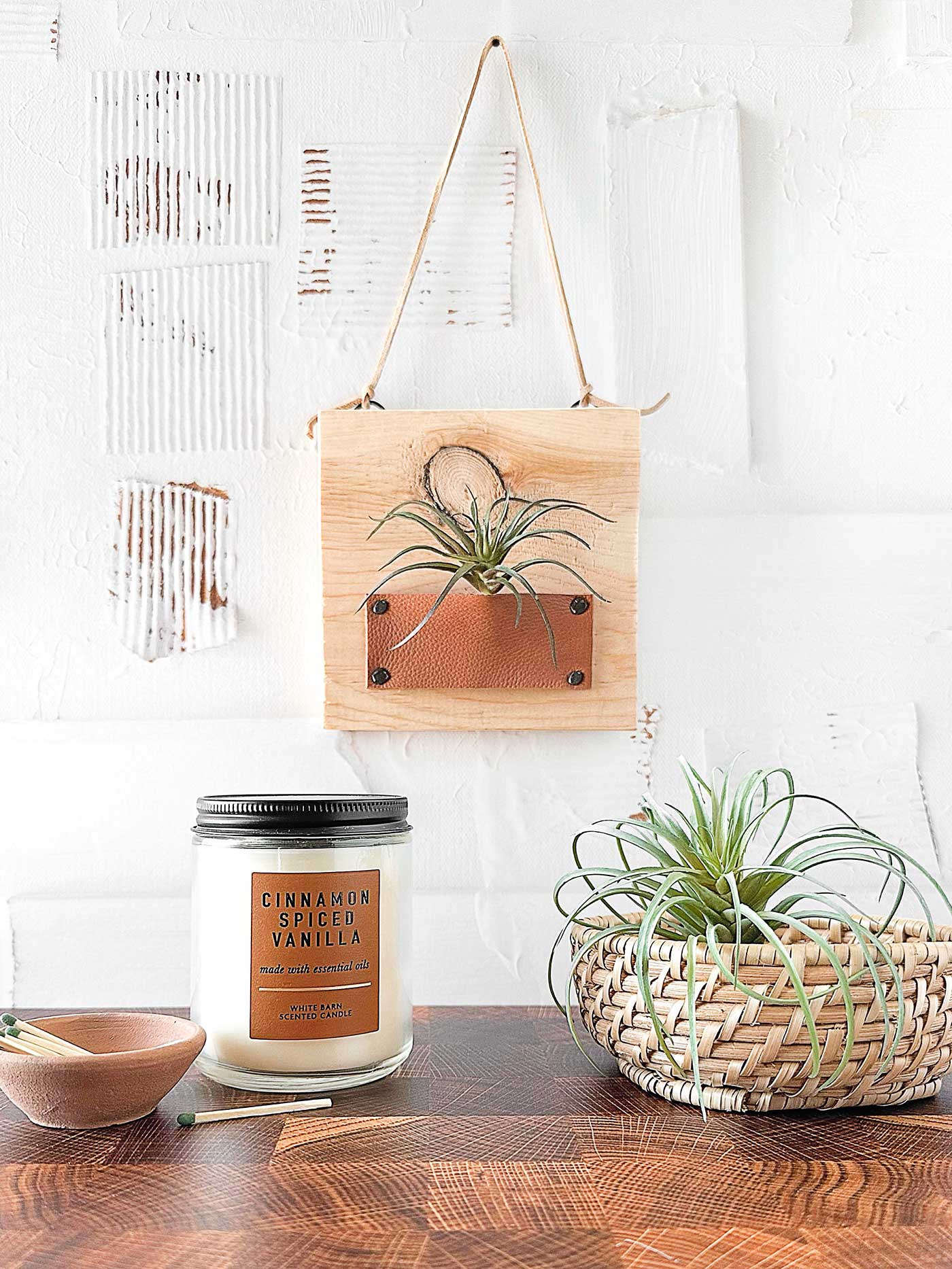 hanging air plant holder pictured with a candle and a basket with another air plant