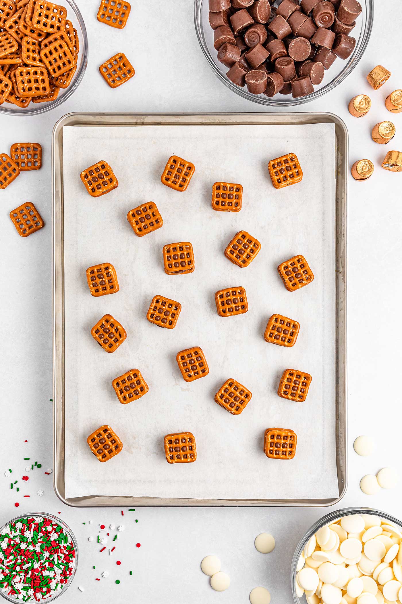 pretzels being placed on top of rolos and pretzels to create a sandwich