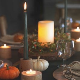 lit candles, pumpkins, plates on a table for thanksgiving celebration