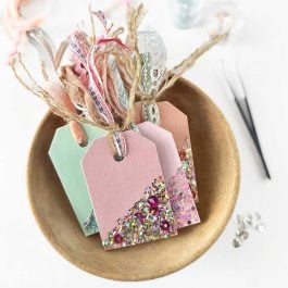 wood gift tags decorated with sparkles in a wood bowl and tied with ribbon