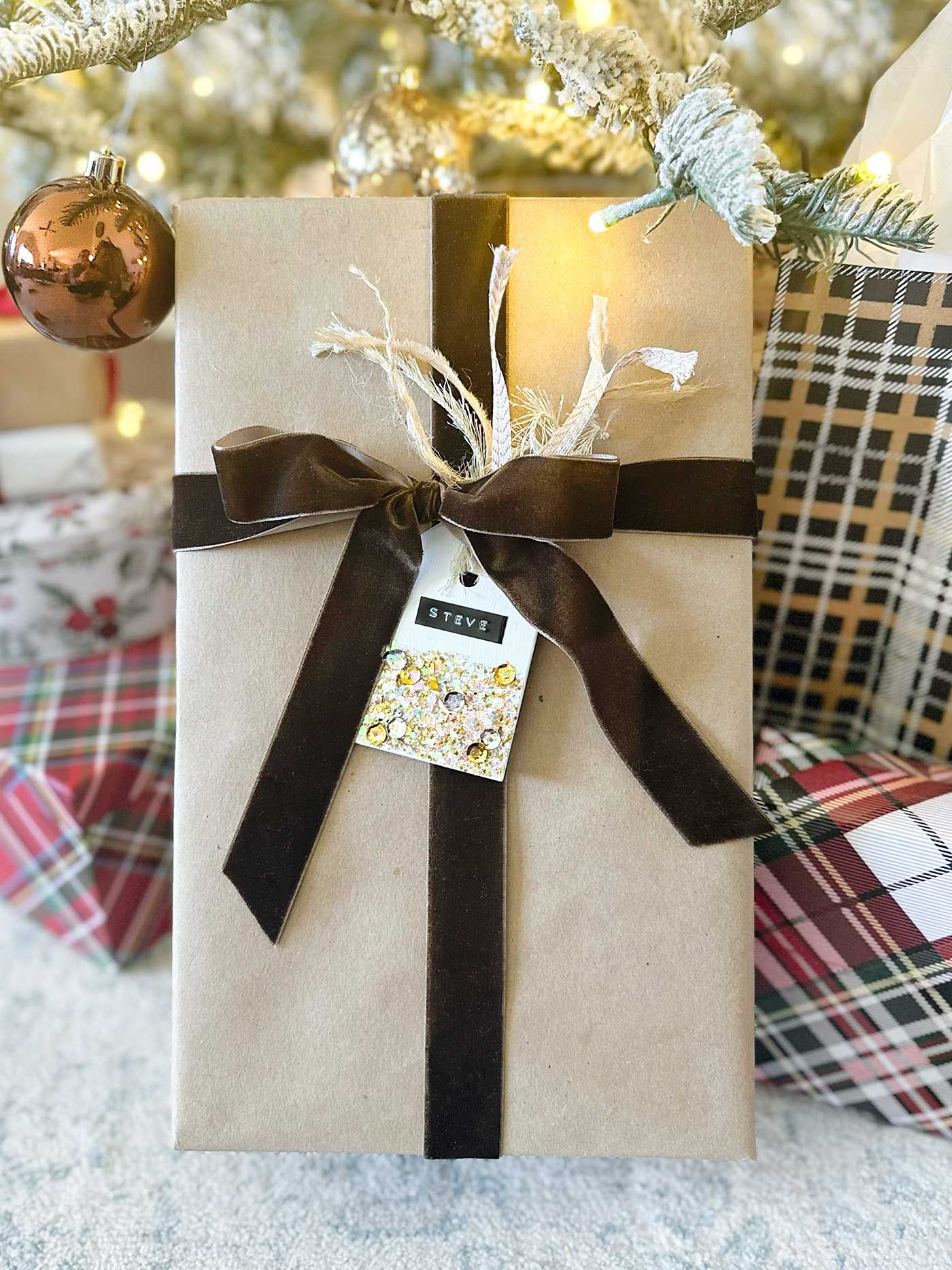 Gift wrapped in kraft paper with a brown velvet bow and a glitter gift tag