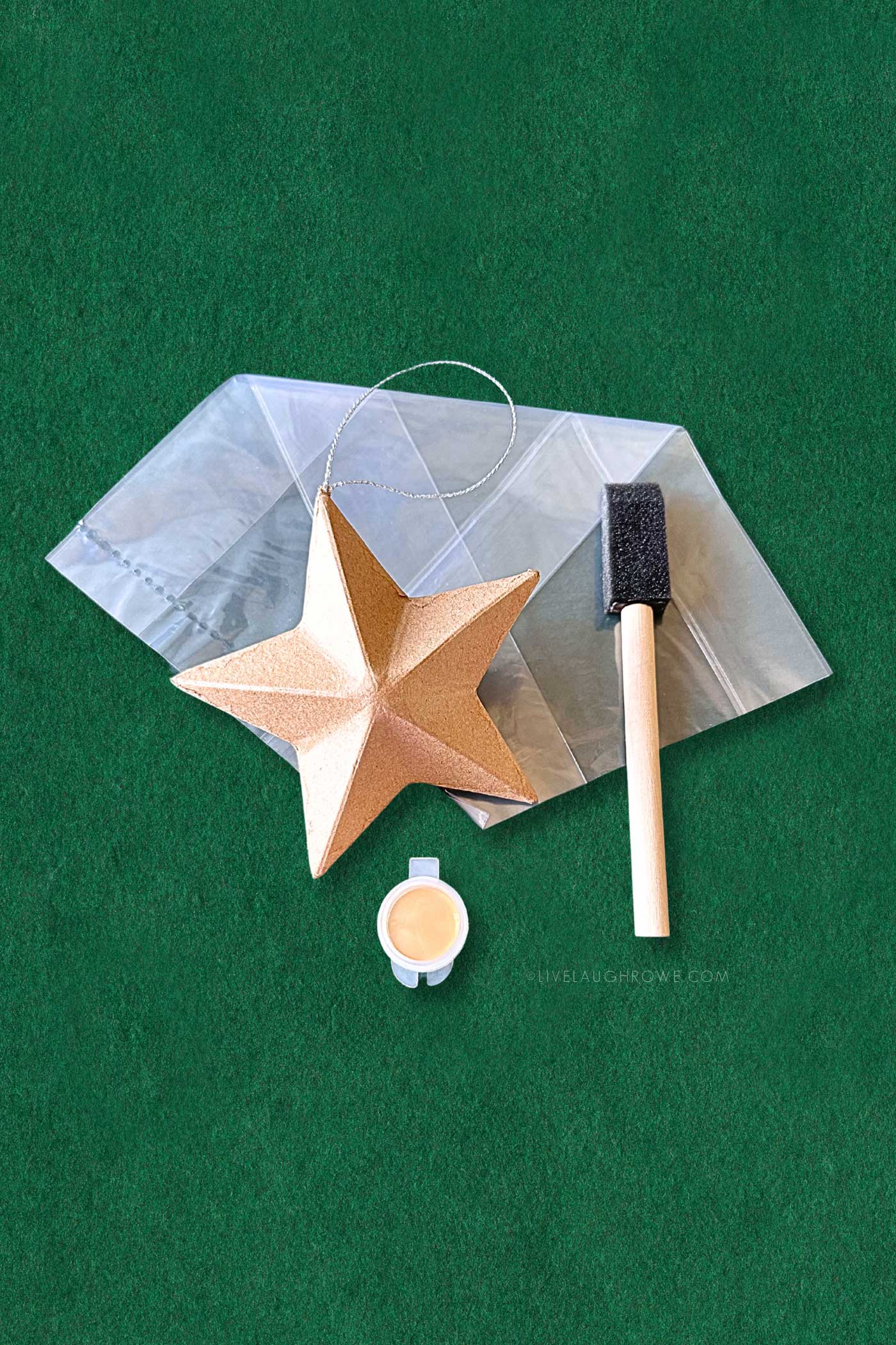 paper mache star ornament with a sponge brush and paint pot. in the backdrop is a clear treat bag