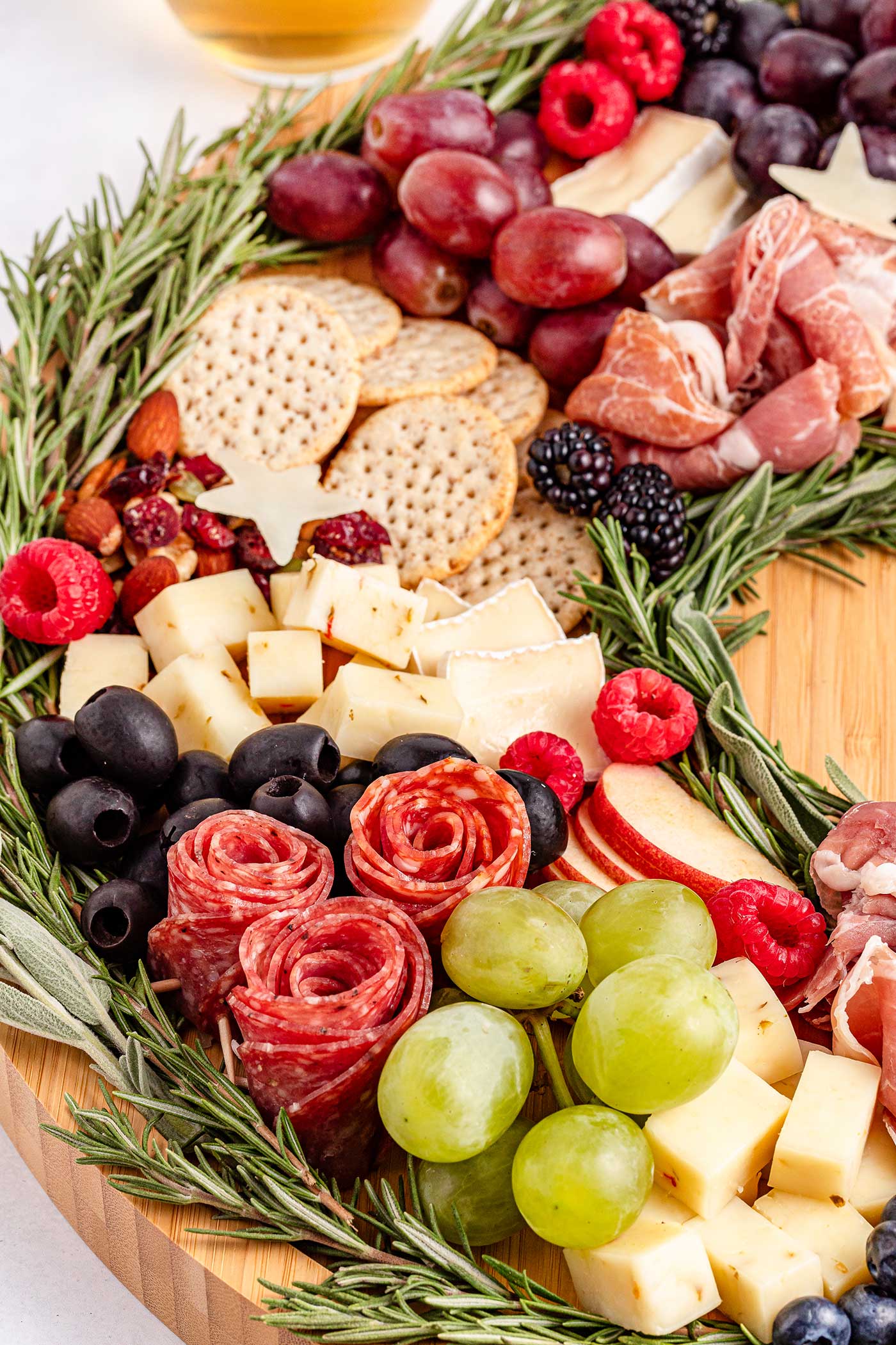 festive snack. round cutting boards with herbs outlining a wreath and other snackables