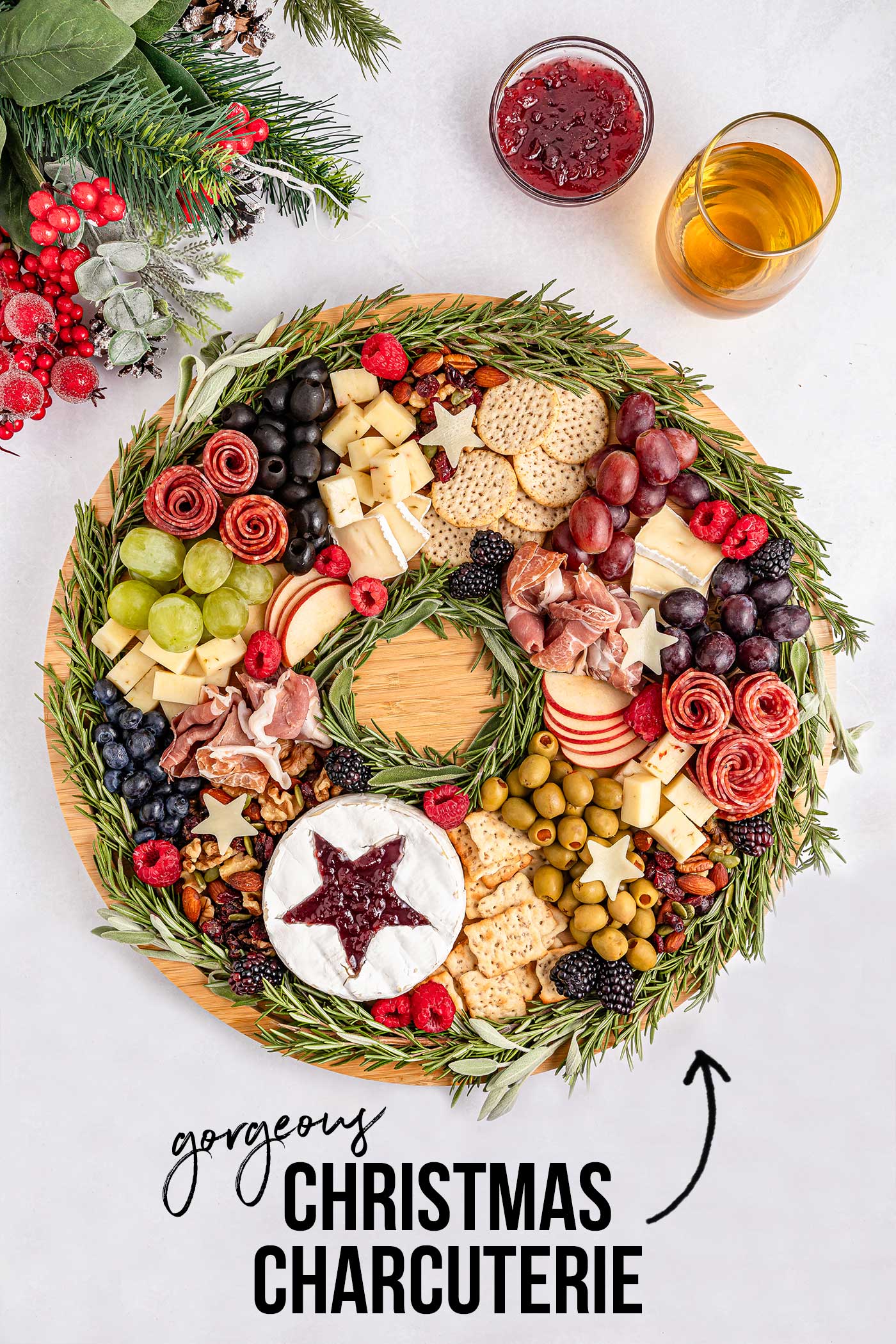 Round cutting board full of meats, cheese, crackers, fruits, nuts and olives. Holiday Charcuterie Board.