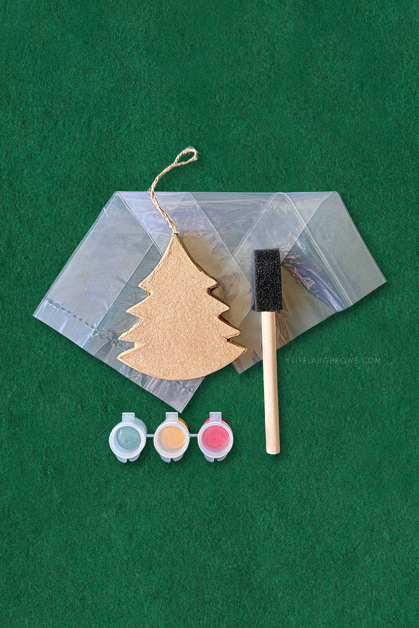 paper mache tree ornament with a sponge brush and paint pots.  in the backdrop is a clear treat bag