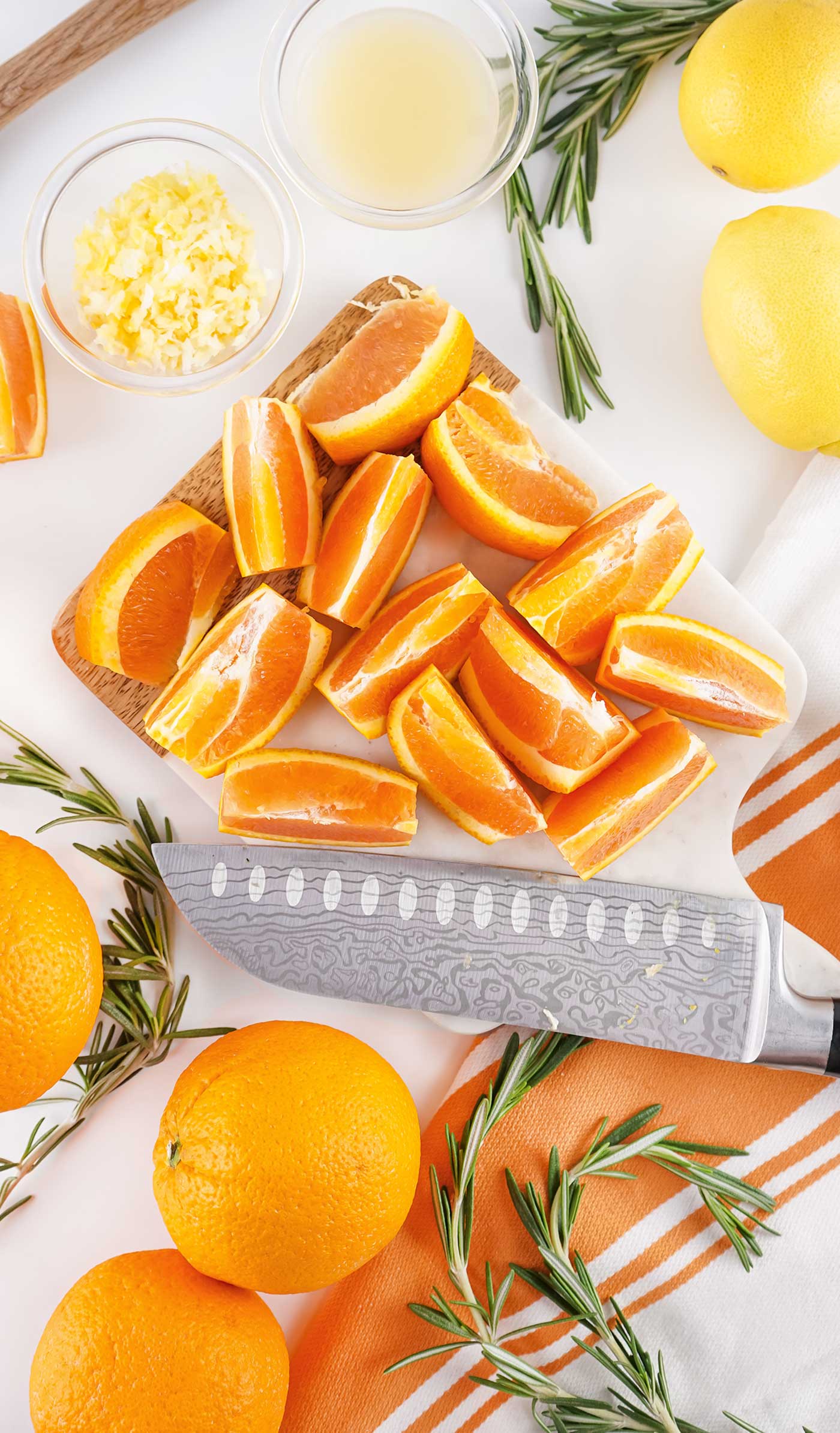 cut oranges on cuttings board with a knife and other ingredients around it