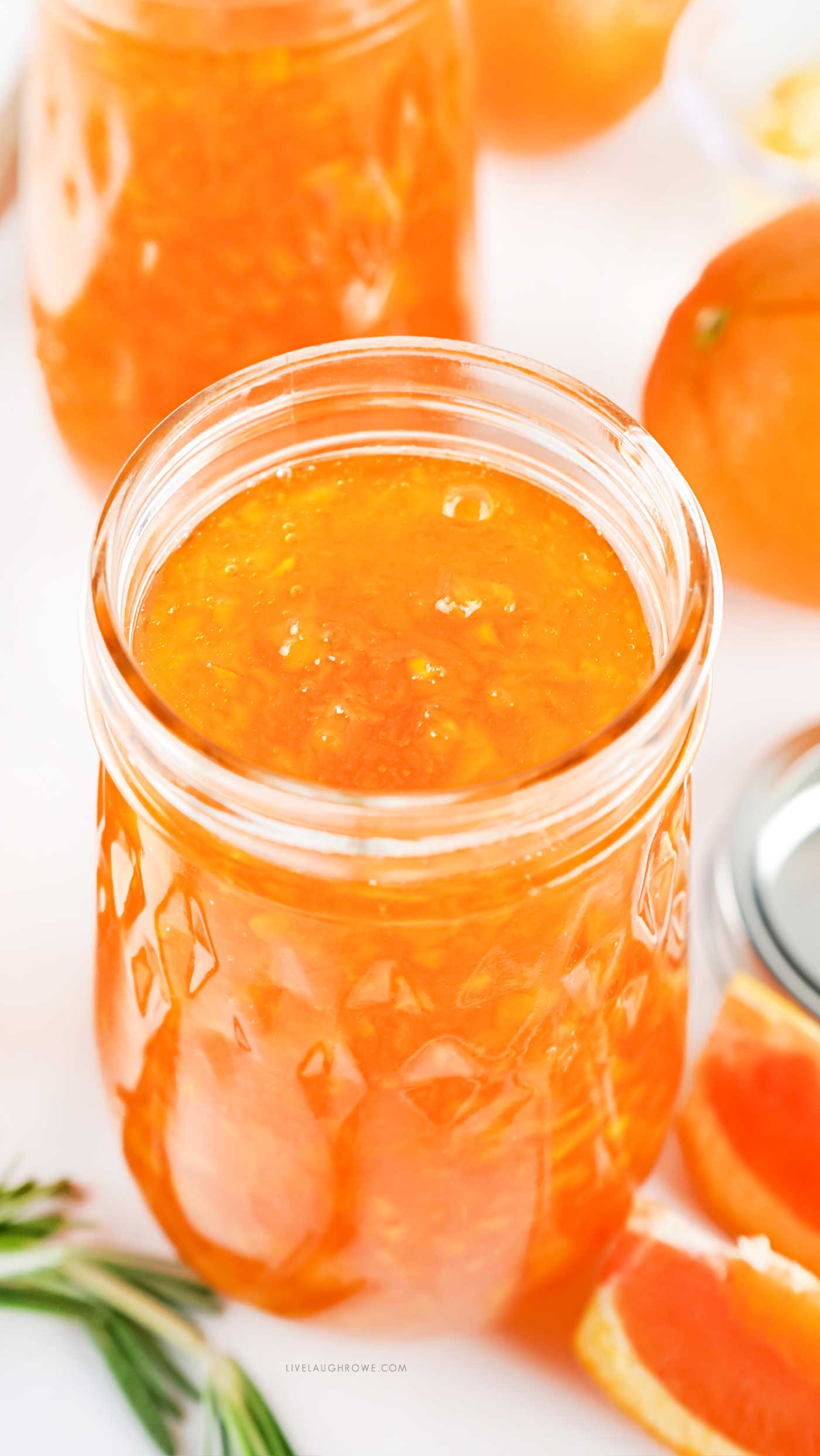 jar of orange marmalade with another jar in the background and orange wedges next to it