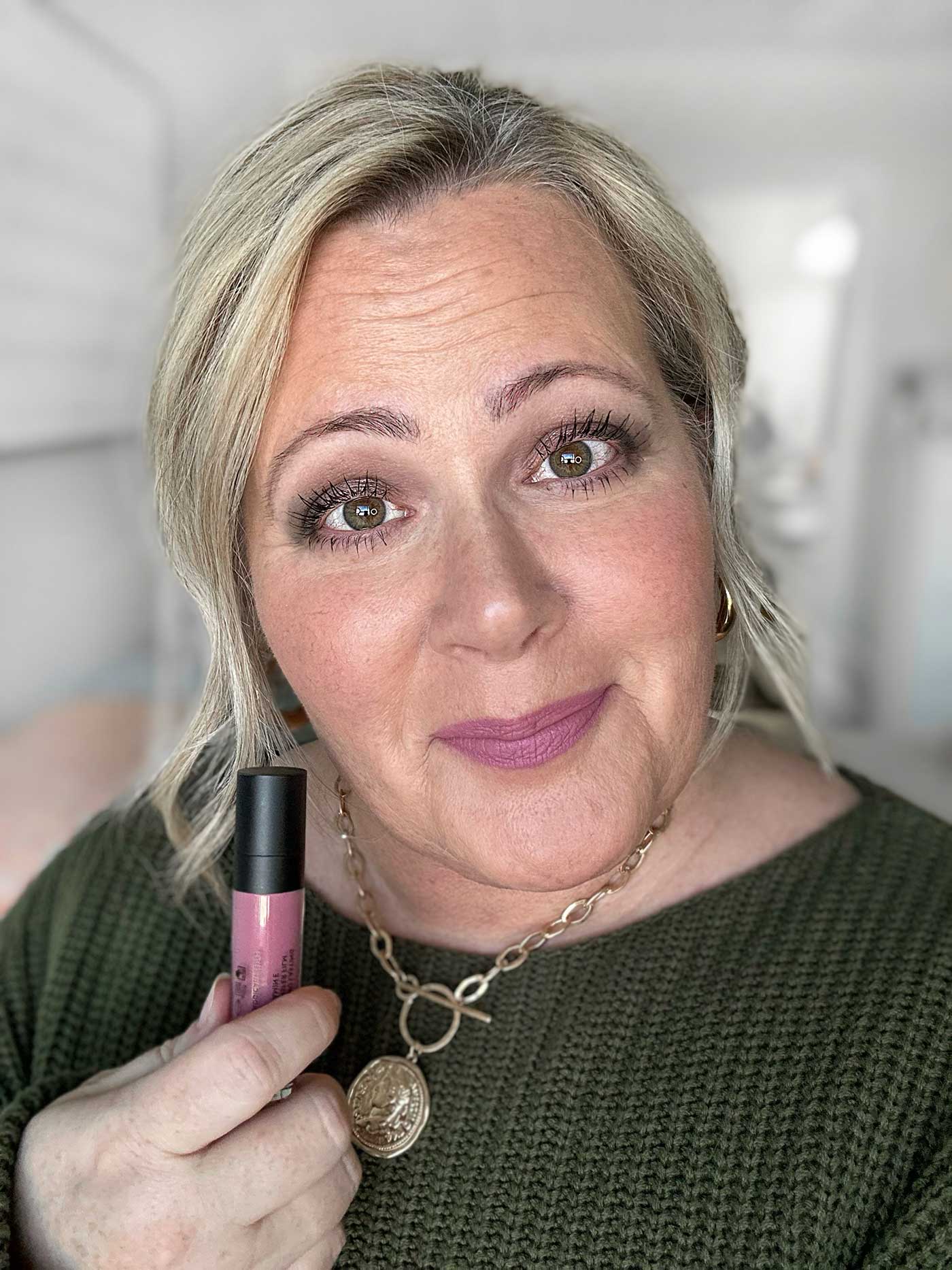 woman wearing makeup and holding a tube of lipstick in her hand from Celesty