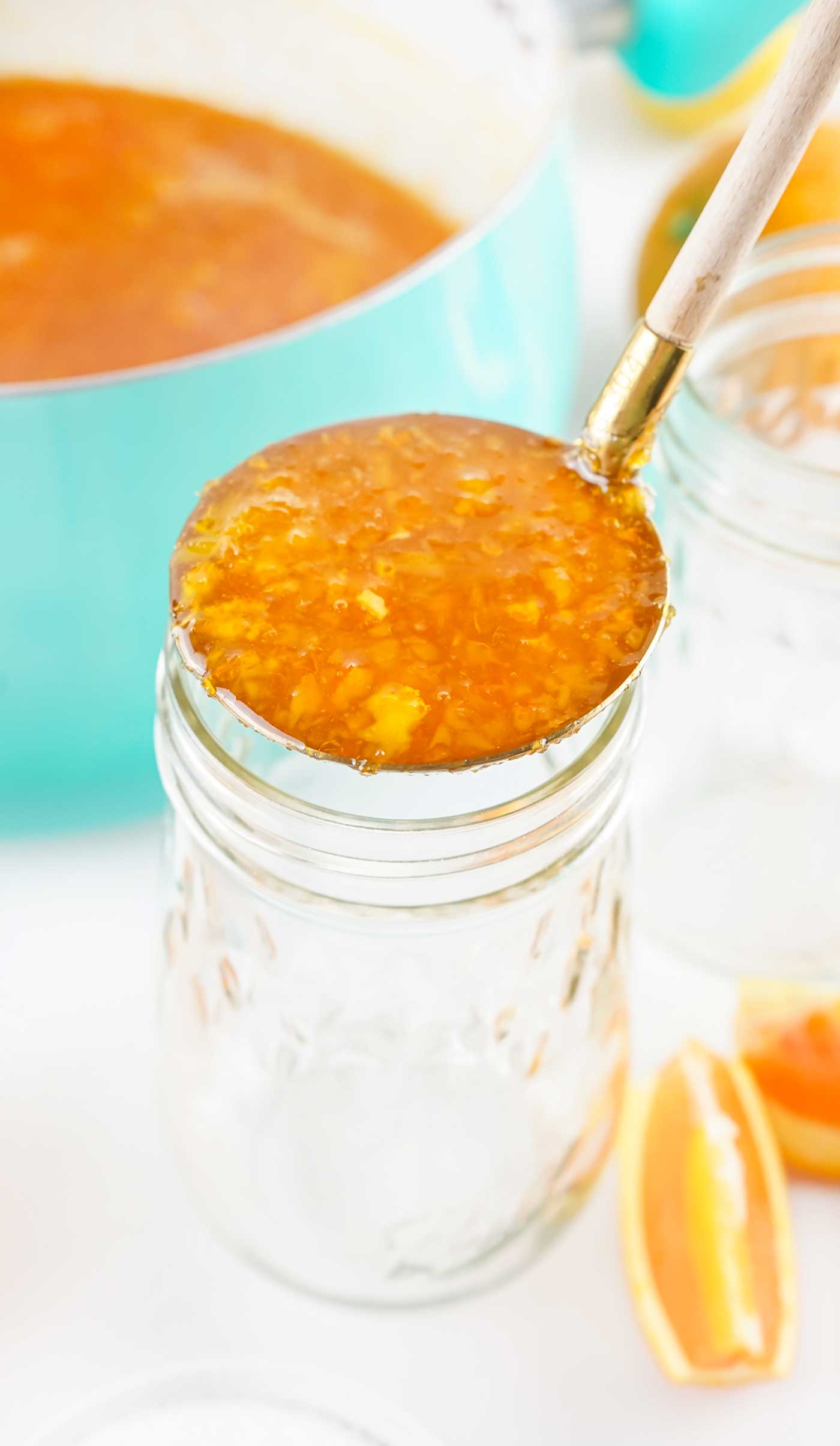 orange marmalade that has cooled and being placed in canning jar