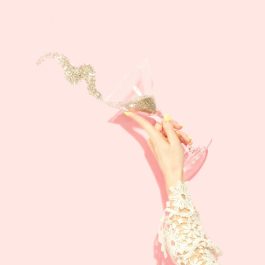 girl holding a martini glass with glitter on a pink background