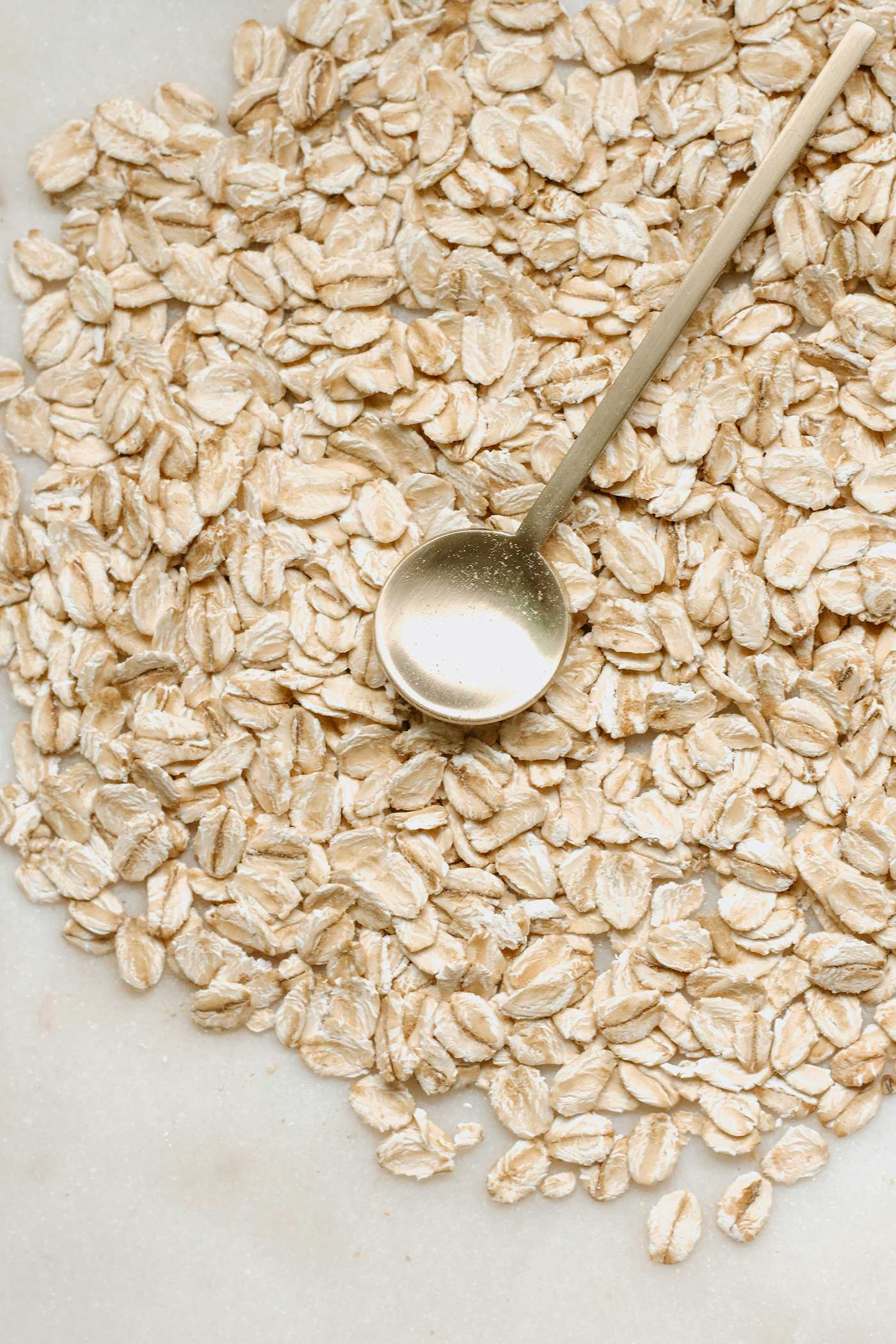 oats poured onto a flat surface with a gold spoon setting on top