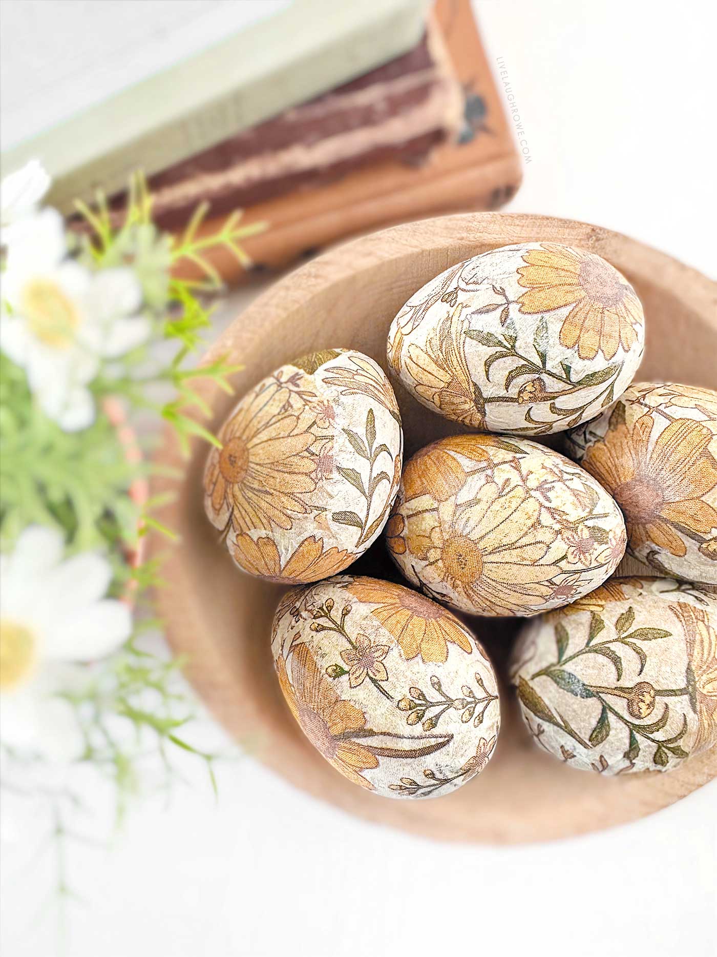 lovely decoupage easter eggs in a wooden bowl with blurred out florals and stack of books