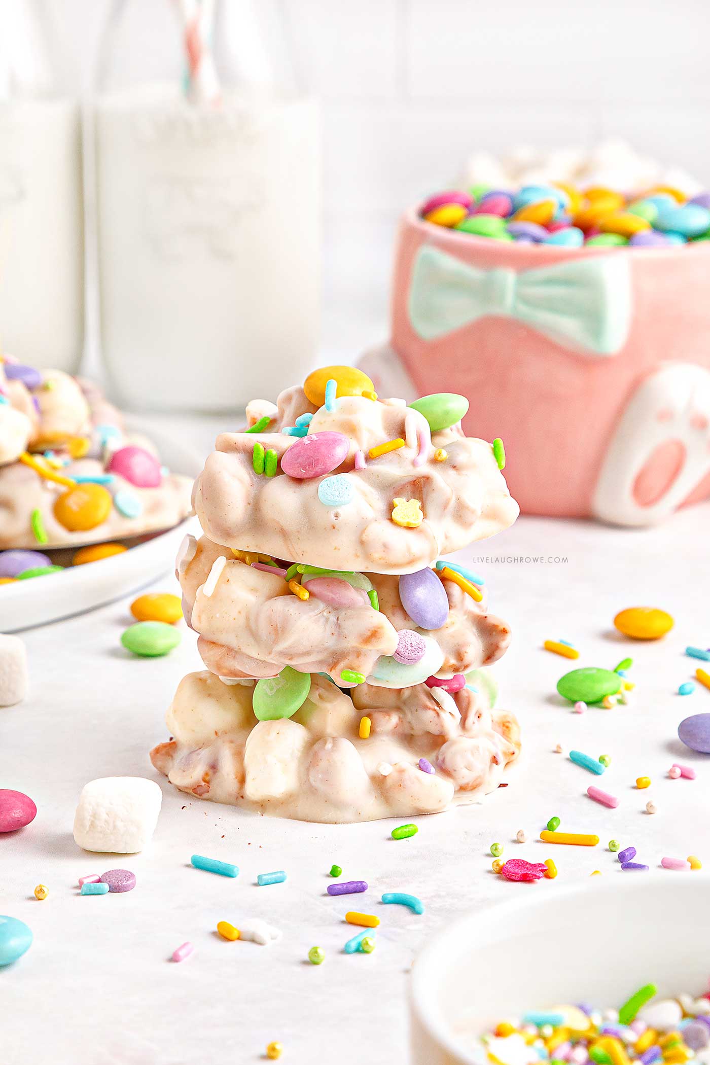 Stacked Easter Candy with sprinkles scattered around it with milk jugs and an Easter mug in the background