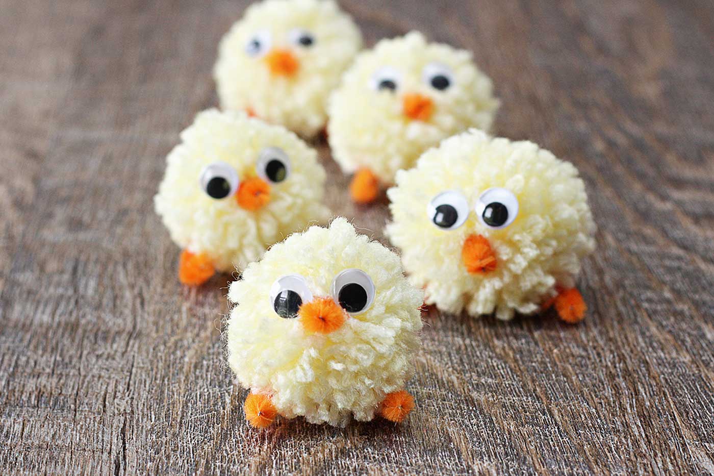 five little googly eye chicks standing on wood background 