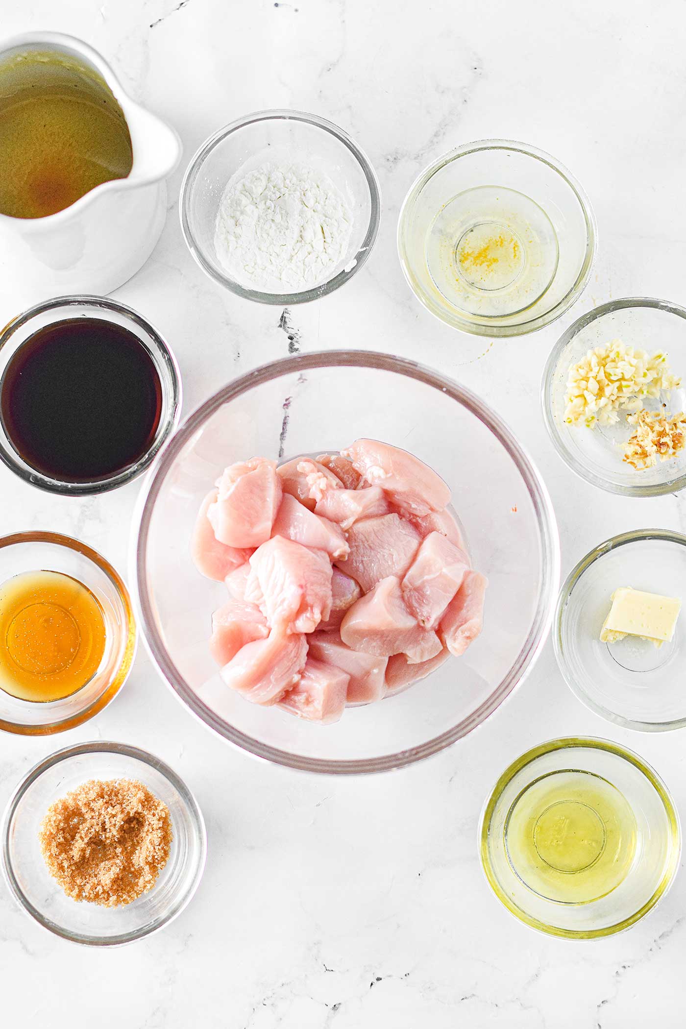 prep bowls filled with ingredients surrounding a bowl of cut chicken