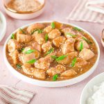 asian chicken meal with napkins, rice and a bowl of sesame seeds around it