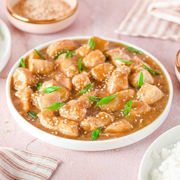 asian chicken meal with napkins, rice and a bowl of sesame seeds around it