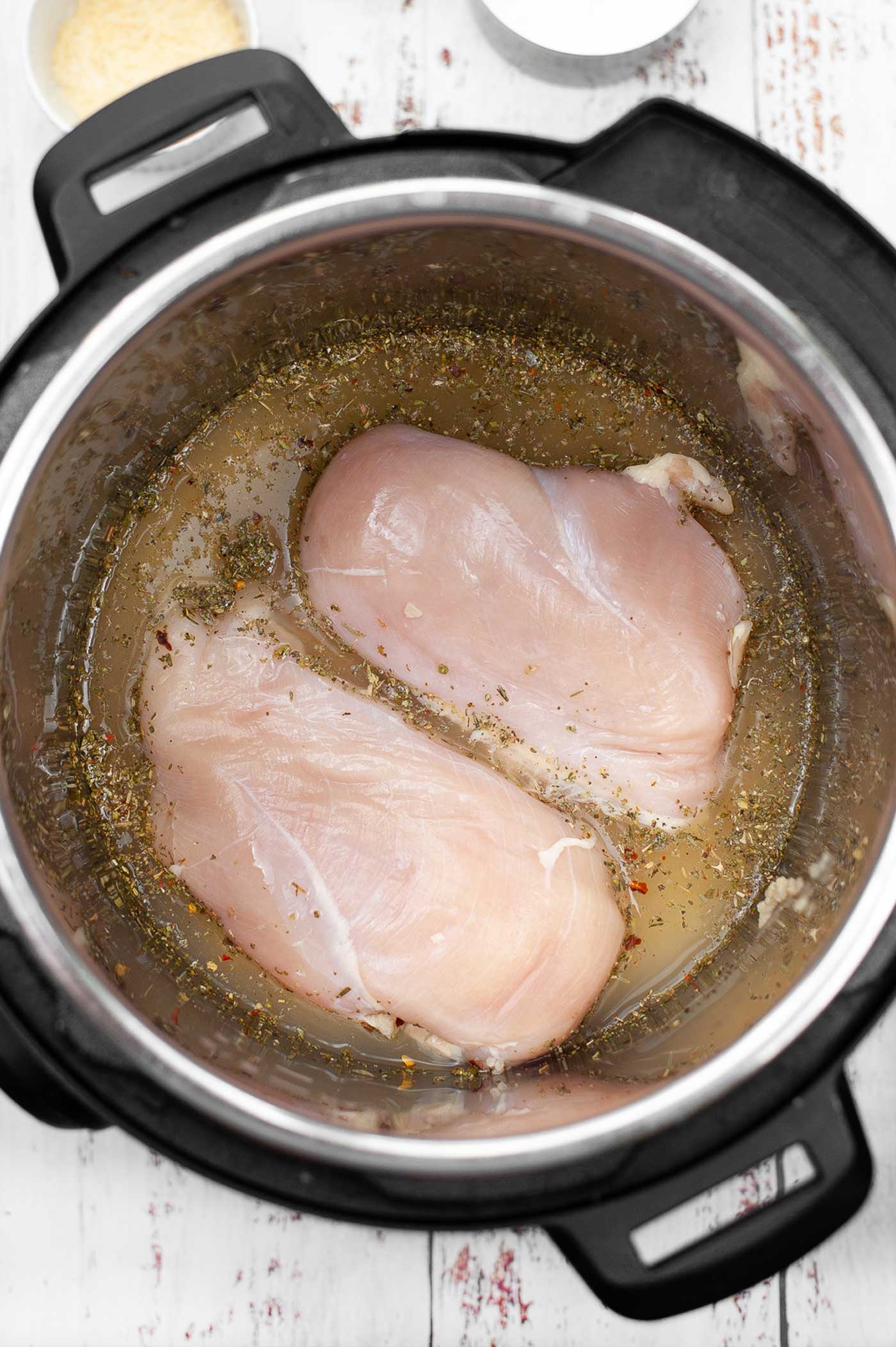 chicken, chicken stock and herbs placed into the instant pot