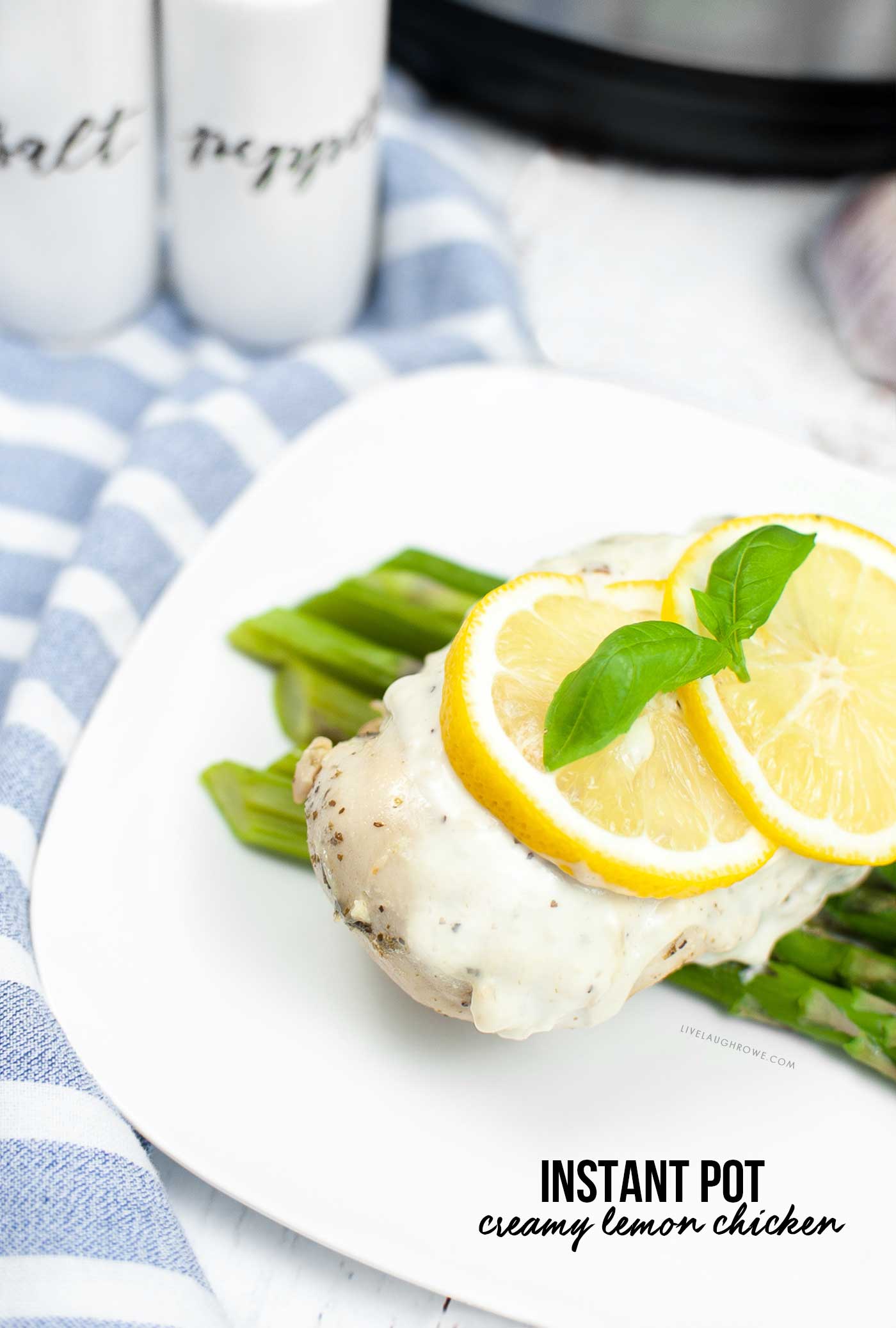 creamy lemon chicken plated with salt and pepper shakers and an instant pot in the background. there is a text overlay with the dishes name: Instant Pot Creamy Lemon Chicken