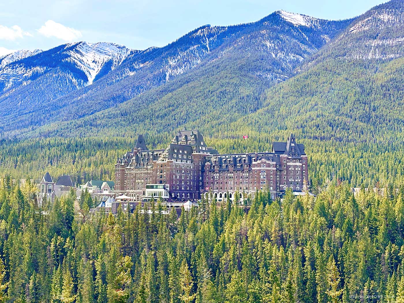 a castle looking hotel nestled among the trees and mountains