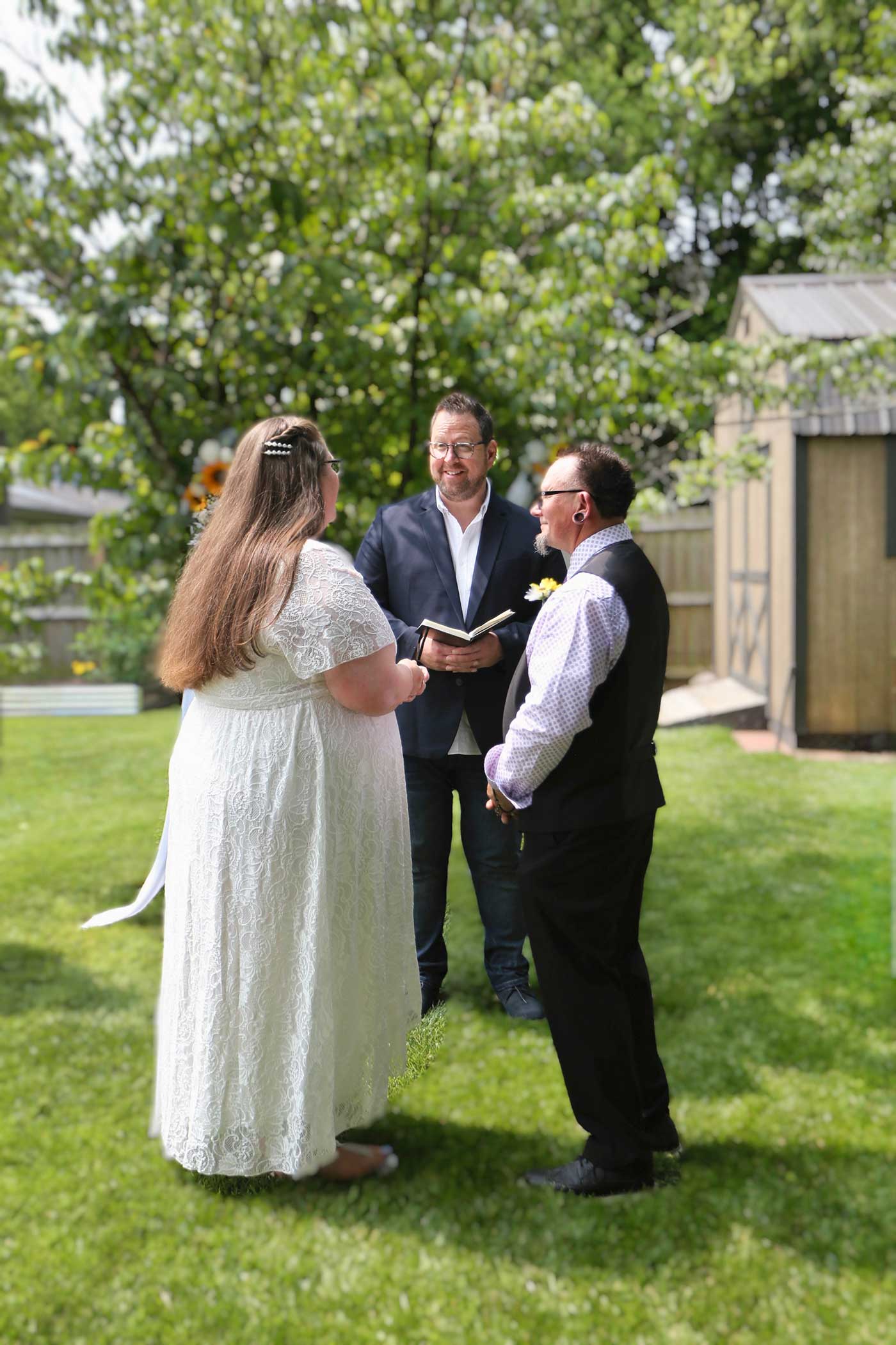 bride, groom and minister at a backyard wedding