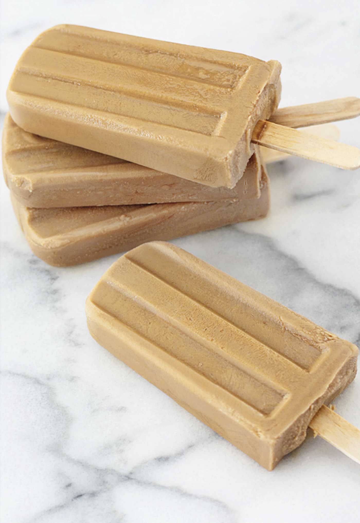 caramel macchiato popsicles placed on top of each other on a marble slab