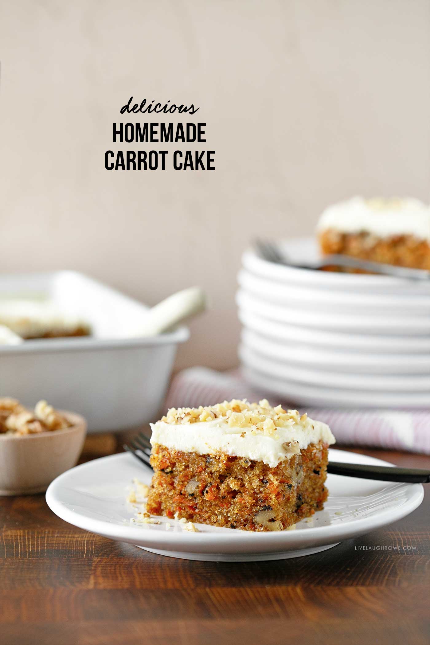 slice of carrot cake on a white plate with a cake pan and stack of plates. photograph has text stating delicious homemade carrot cake