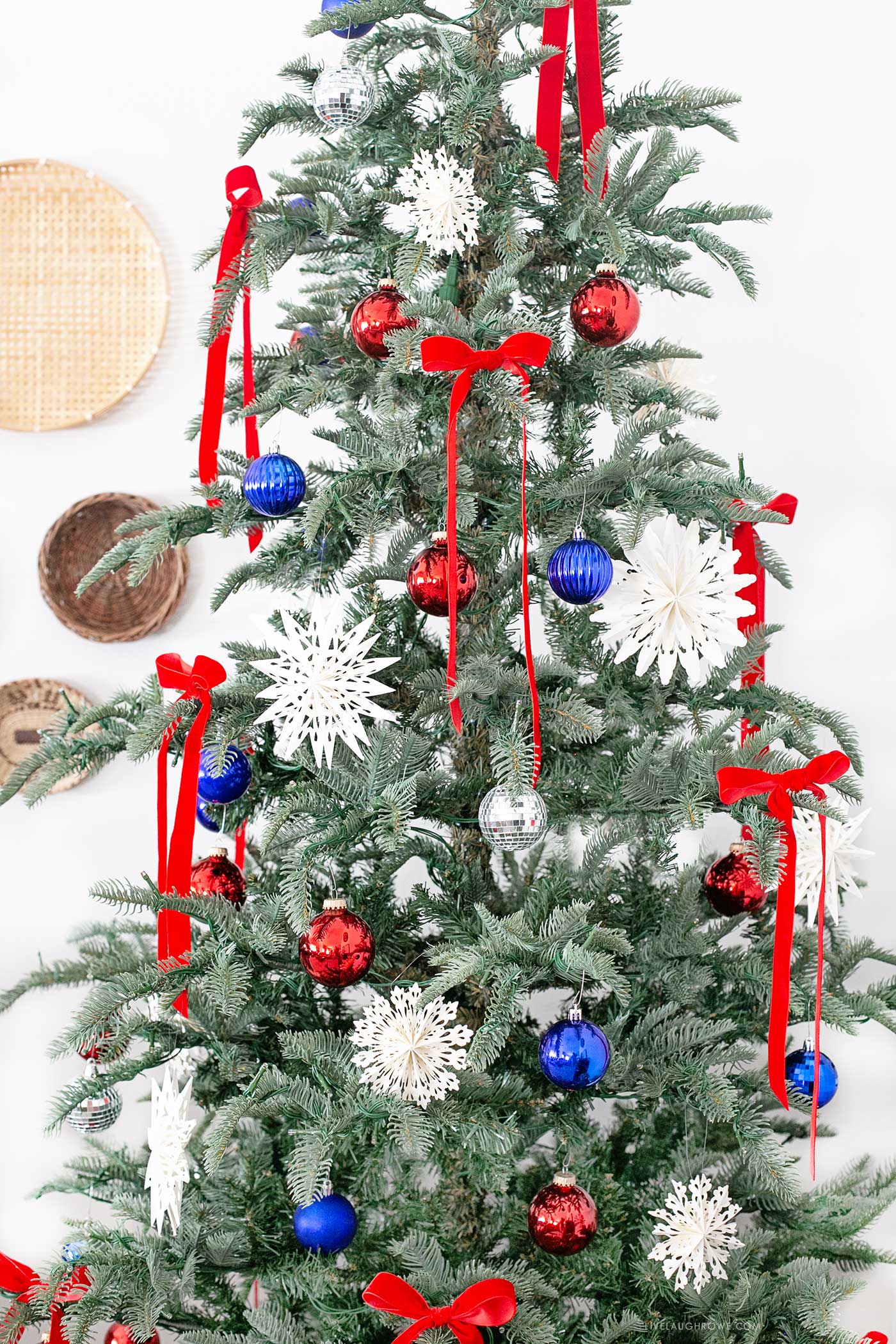 closer look at Christmas in July decorated tree, styled with red velvet bows, blue and silver ornaments, and oversized white stars for a festive, summer-ready holiday celebration