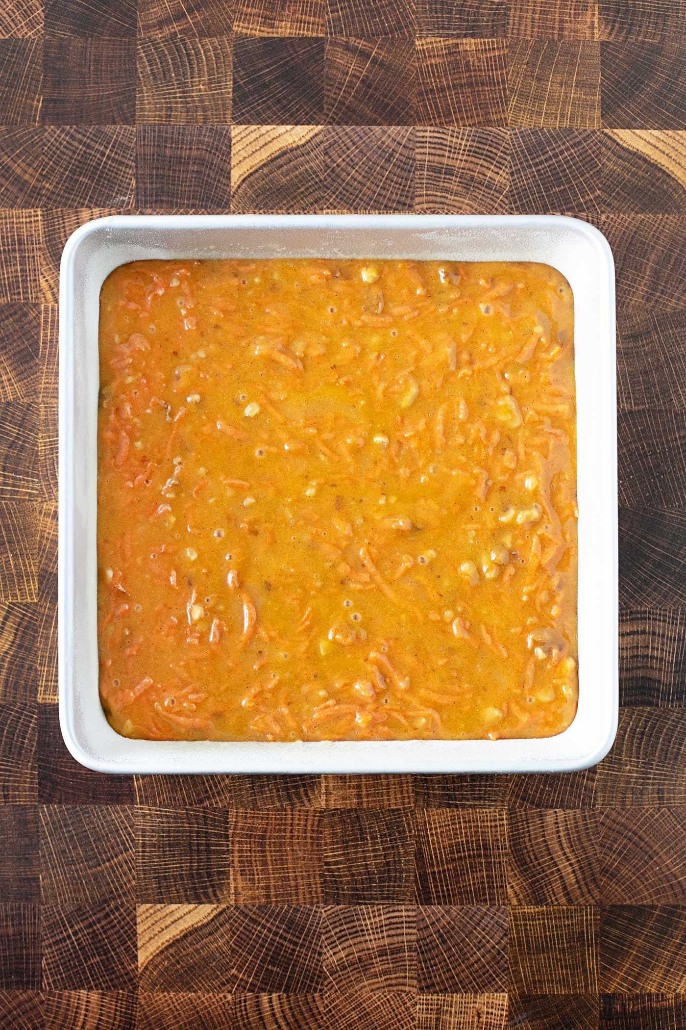 Carrot Cake batter poured into a floured and greased 8x8 cake pan, ready for the oven