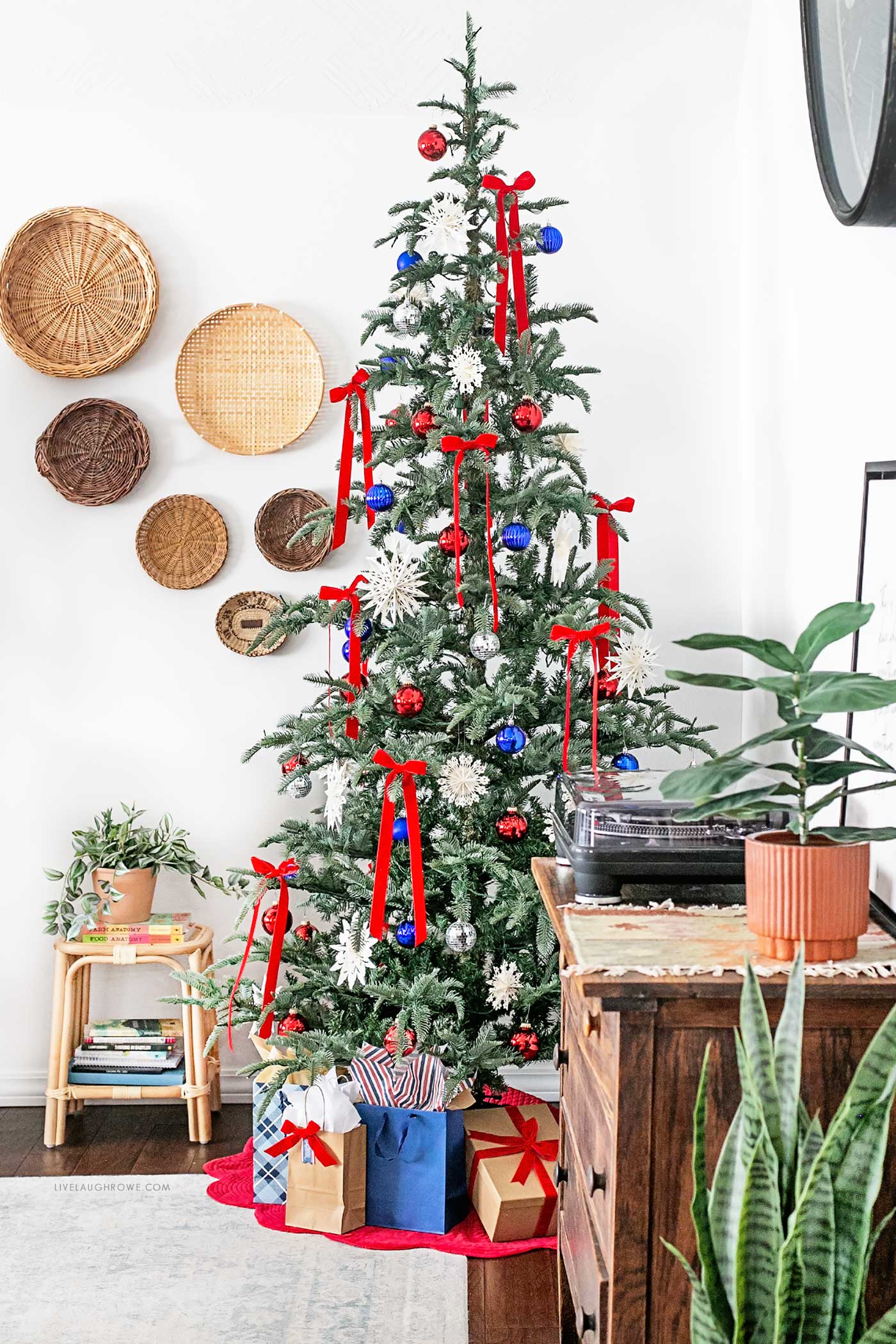 Patriotic Christmas tree for July, styled with red velvet bows, blue and silver ornaments, and oversized white snowflakes for a festive, summer-ready holiday look.