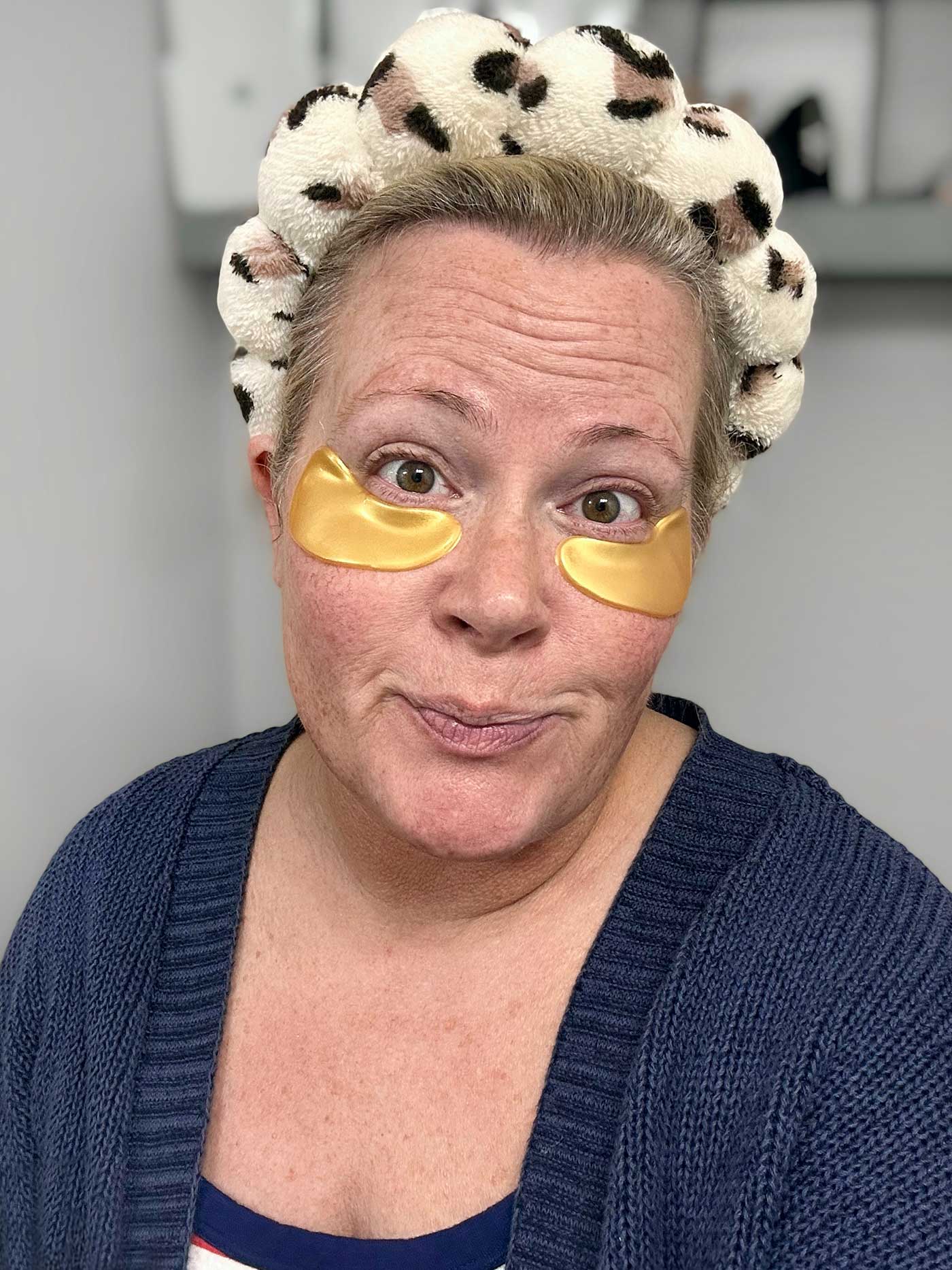middle-aged woman wearing a headband and eye masks for a little self care
