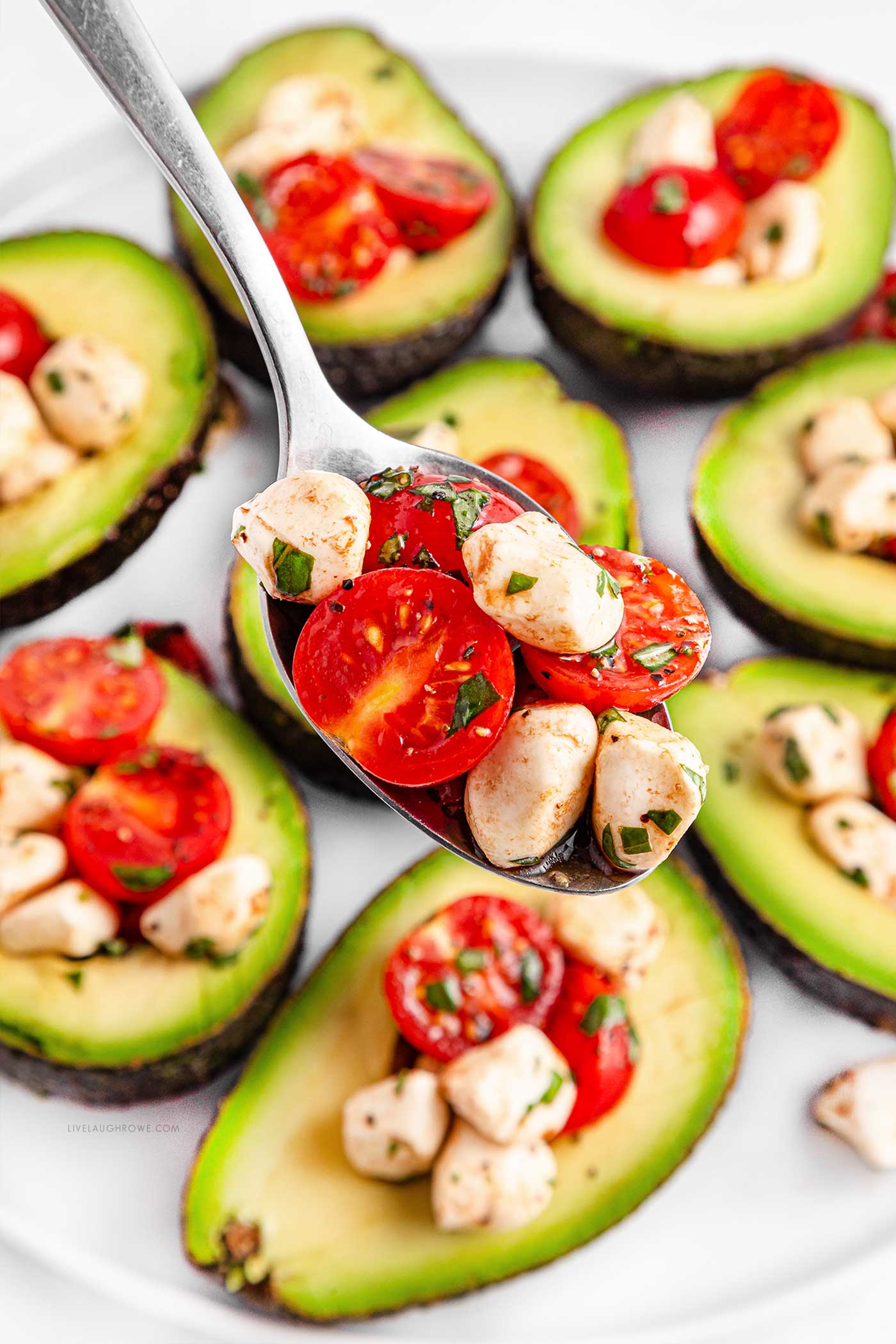 spooning the caprese filling into avocado halves