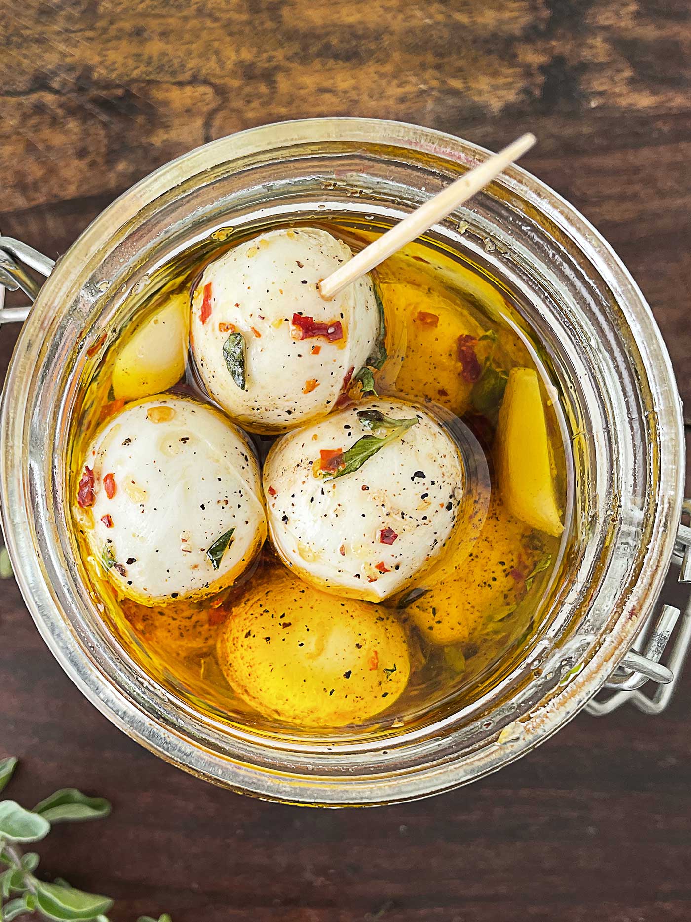 jarrednmozzarella cheese sitting in marinade, one with a toothpick in it
